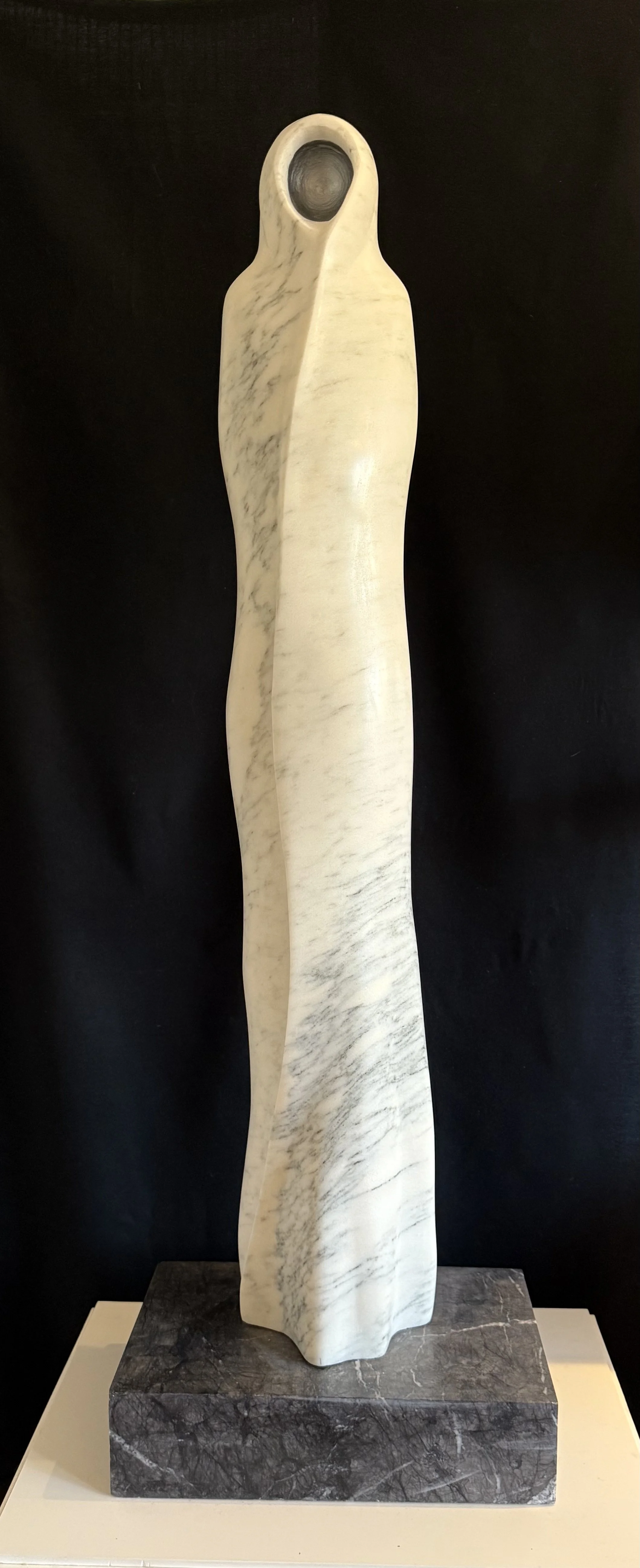 Second Place Sculpture, Elisa Adams, "the Crone". Carved from ancient Vermont marble, she sits nearly five feet high on her hill. The natural play of light and shadow across her surface mirrors the solitude of the Crone. She rests in stillness: an an