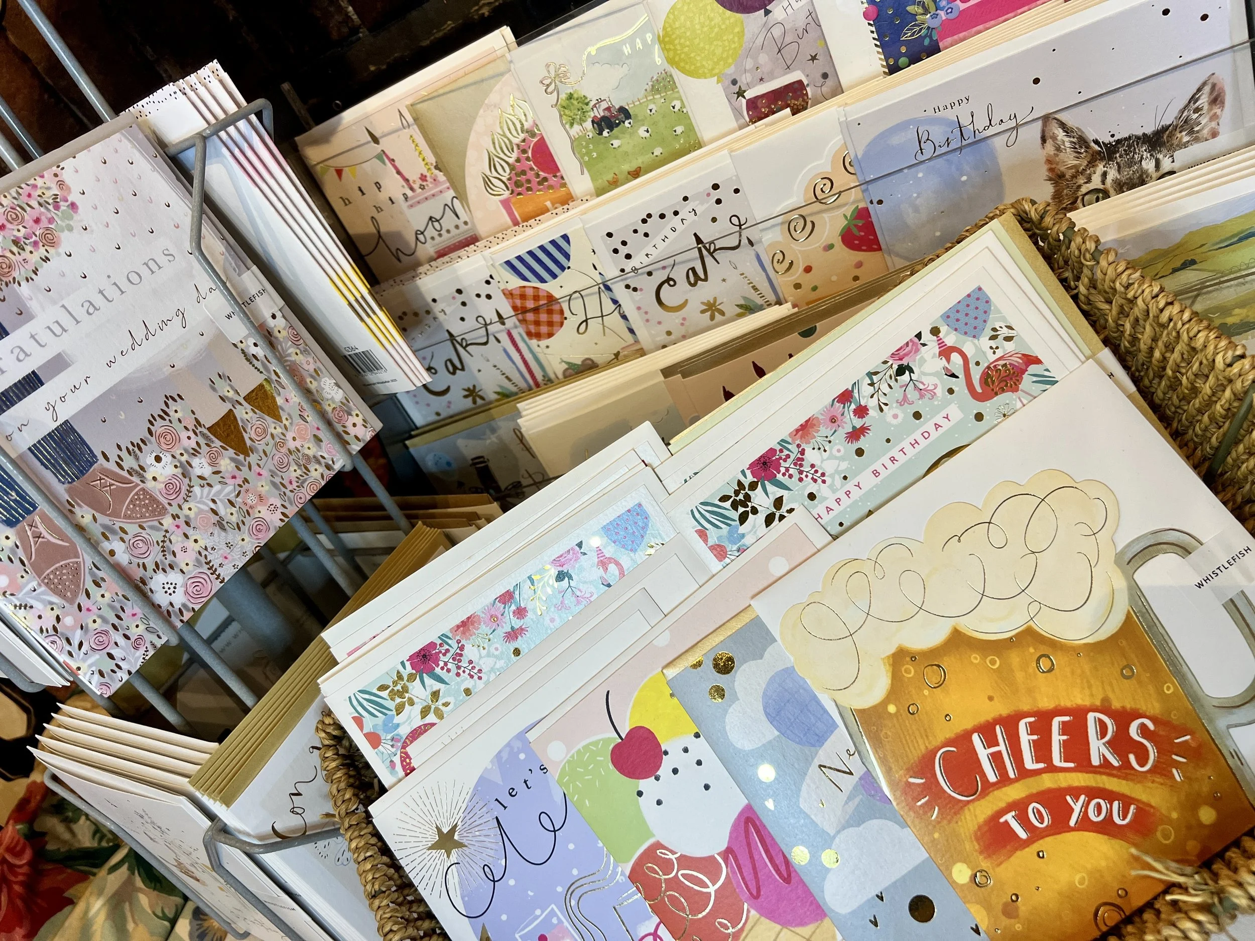 A display of various colorful greeting cards, including birthday and congratulations cards, on a rack in a store.