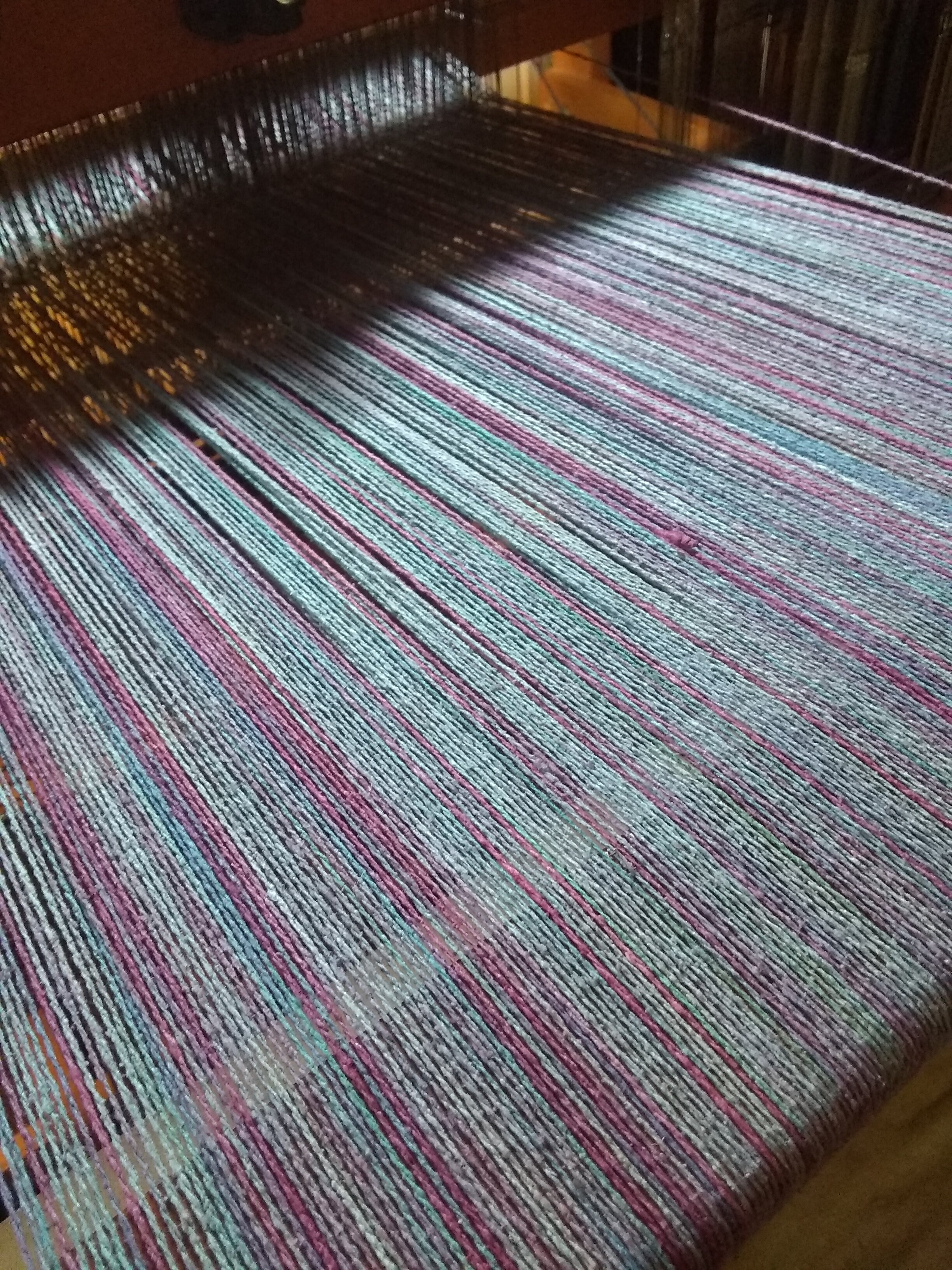 Once the loom is threaded, the warp (yarns on the loom) must be kept at a consistent tension to achieve an even weave structure.