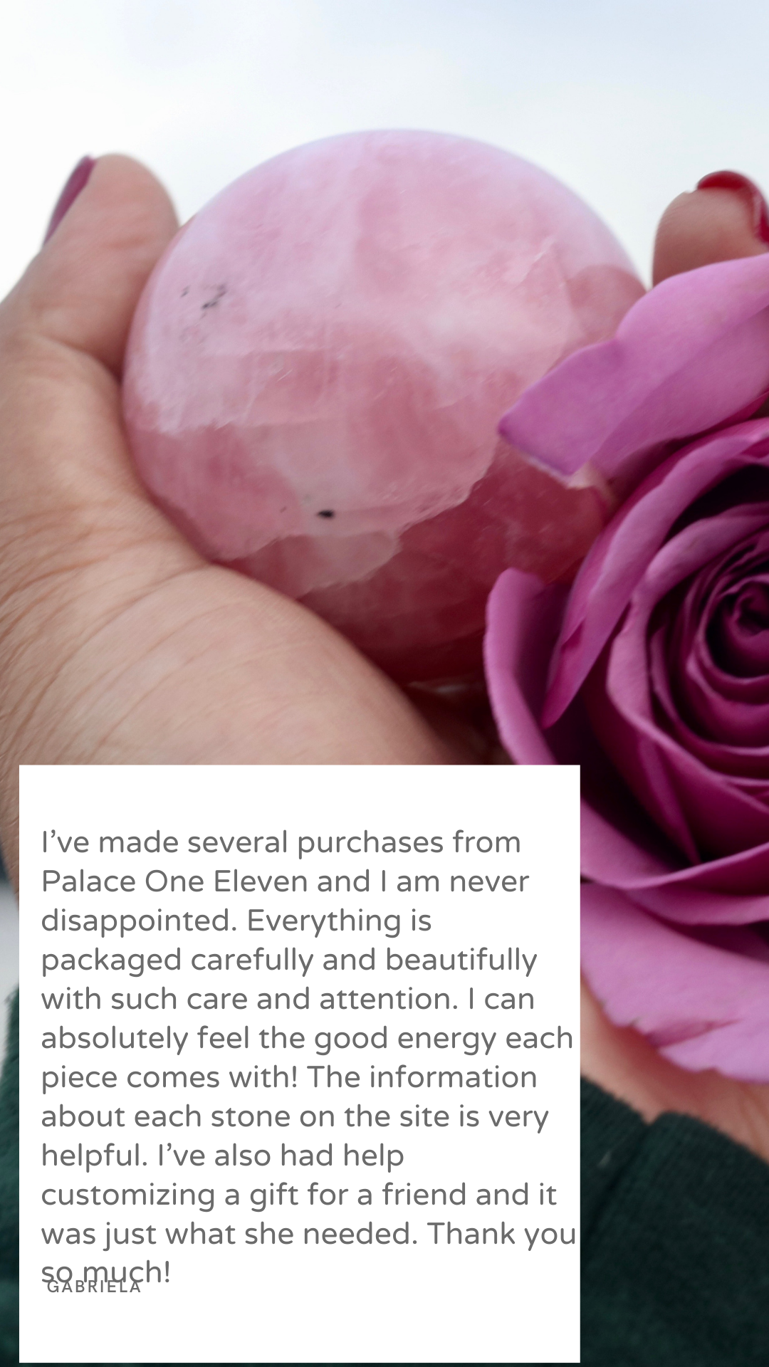 Close-up of a hand holding a pink polished stone next to a pink rose.