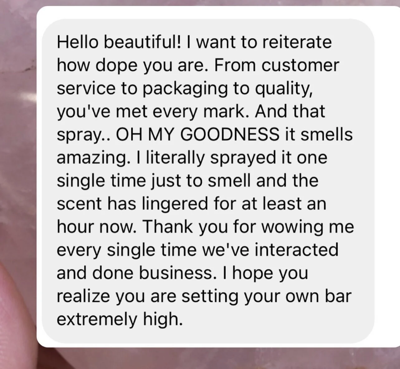A screenshot of a text message expressing admiration and appreciation for a person's product, emphasizing how good it smells and how long the scent lasts.