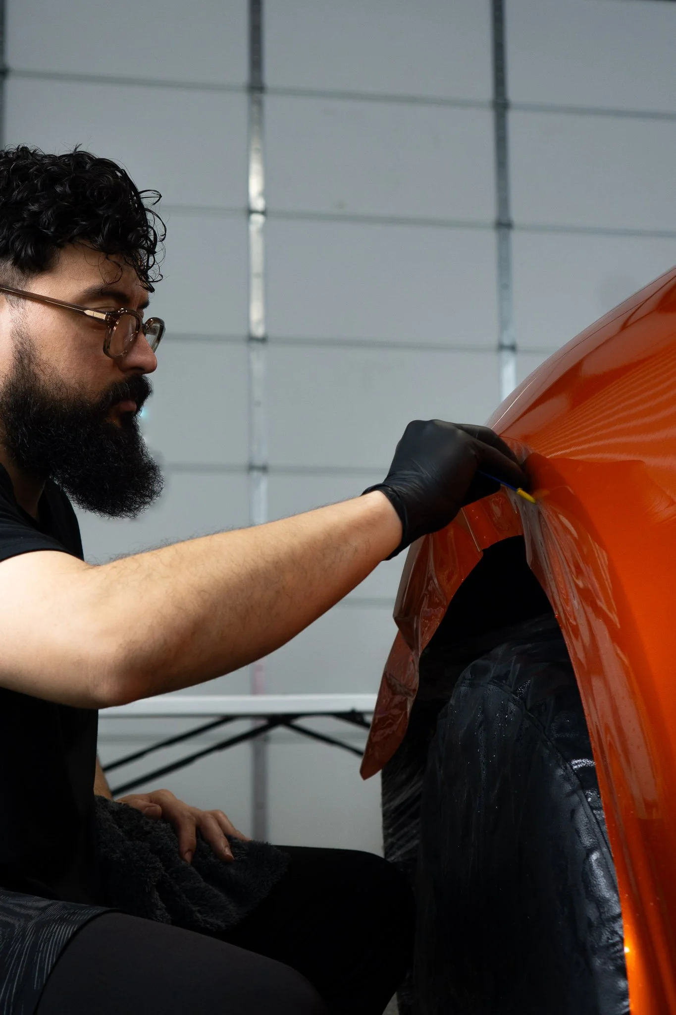 EIGHTYNINE VWS technician wrapping a vehicle fender with orange color change paint protection film in the Little Elm, TX installation studio