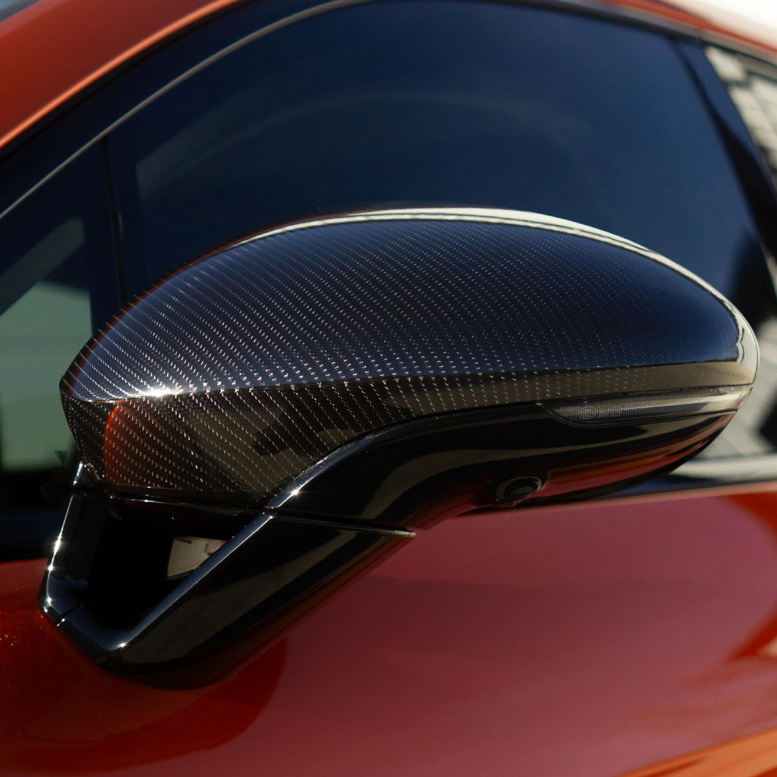 Close-up of a carbon fiber side mirror cap on a dark red vehicle with tinted windows - EIGHTYNINE VWS carbon fiber accessory and window tint services in Little Elm, TX