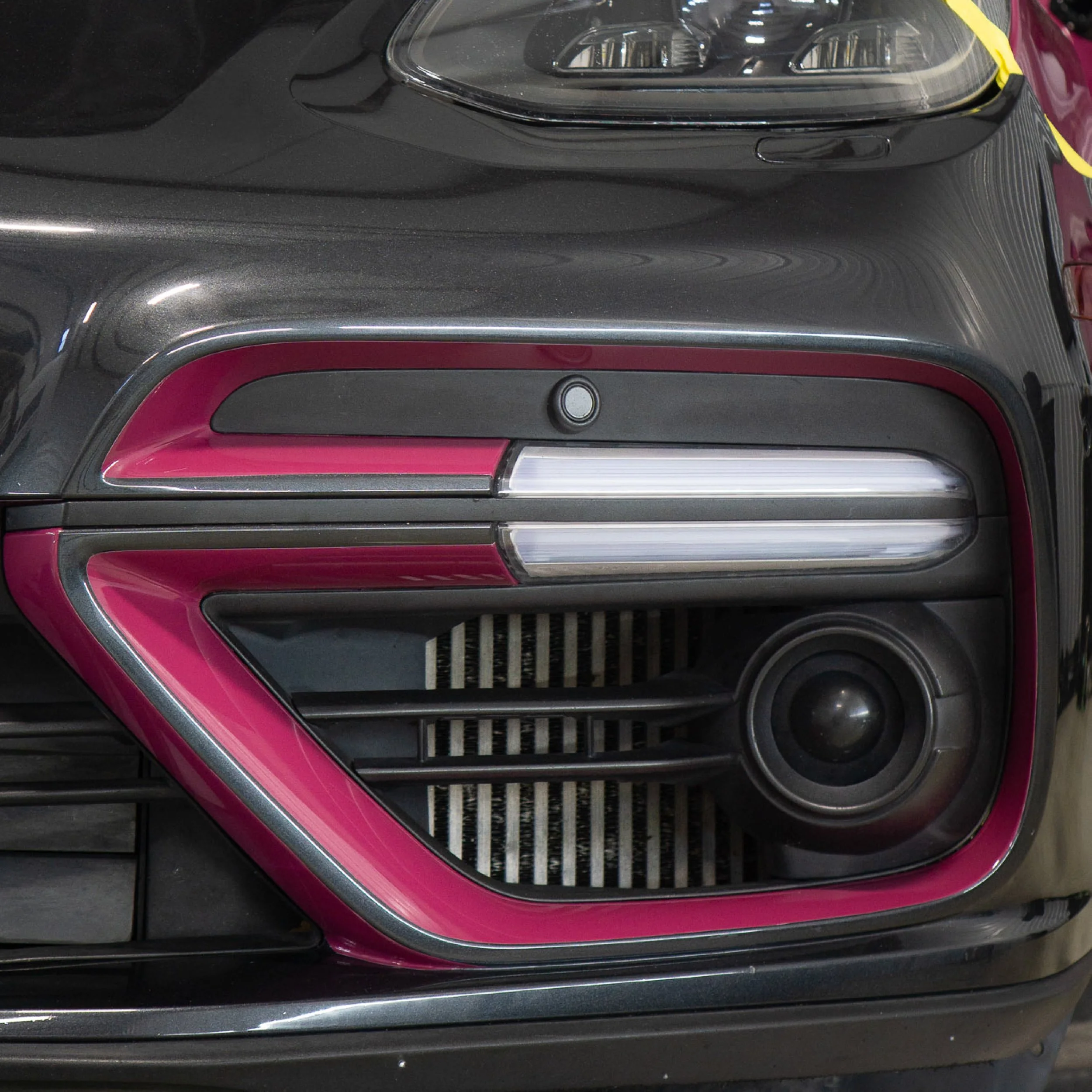 Close-up of a two-tone vehicle wrap in magenta pink and satin chrome on the front fender and headlight - custom color-block vehicle wrap design by EIGHTYNINE VWS in Little Elm, TX