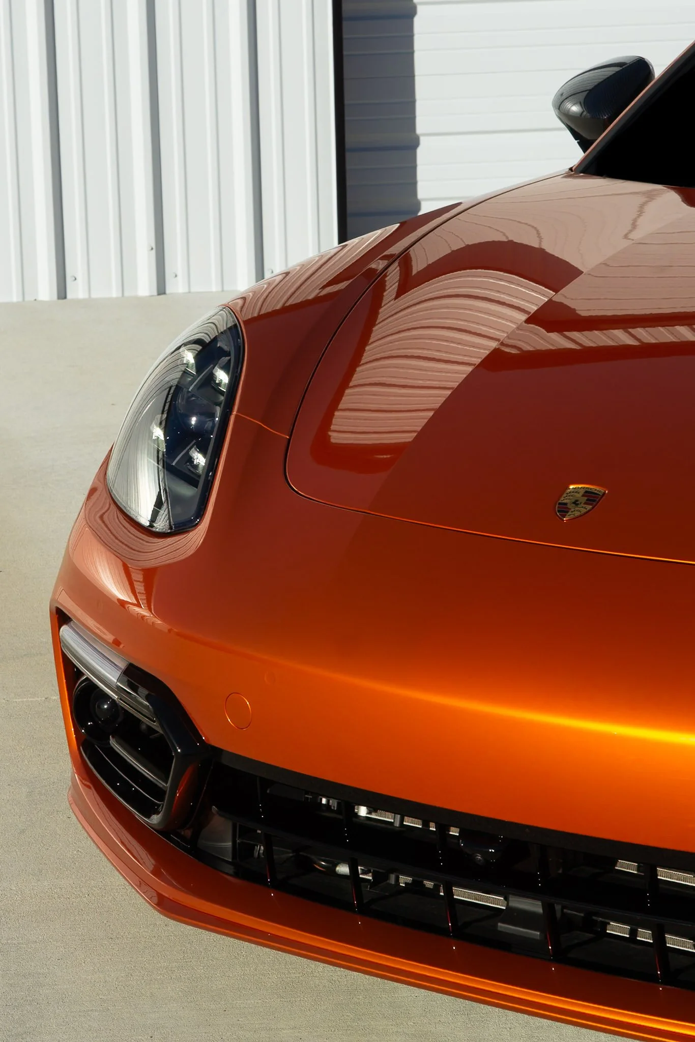 Close-up front view of an orange Porsche 718 Cayman GTS with color change paint protection film, showing the crisp edge finish achieved by EIGHTYNINE VWS in Little Elm, TX