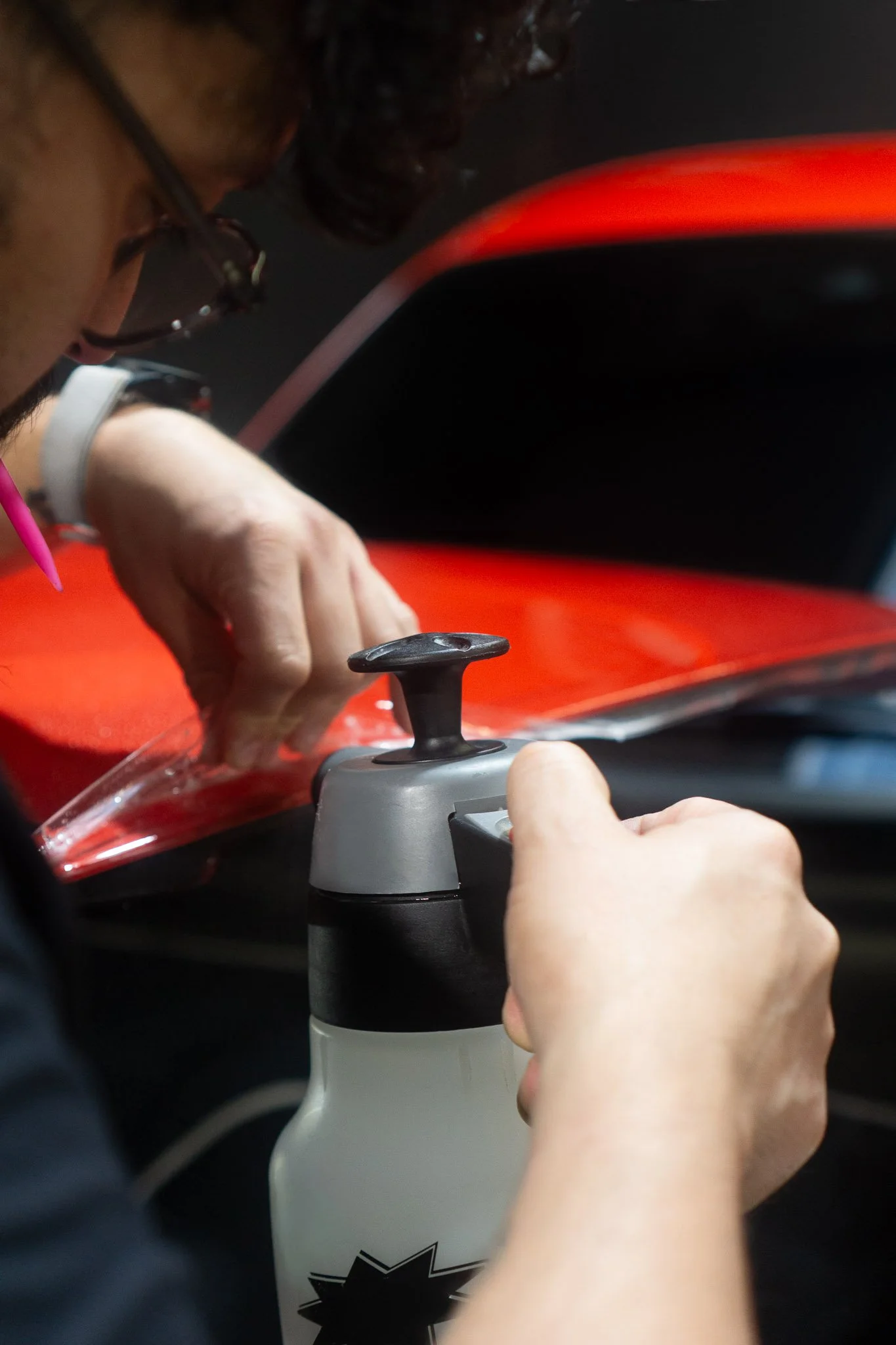EIGHTYNINE VWS technician applying slip solution while installing paint protection film on a red vehicle's side mirror in Little Elm, TX