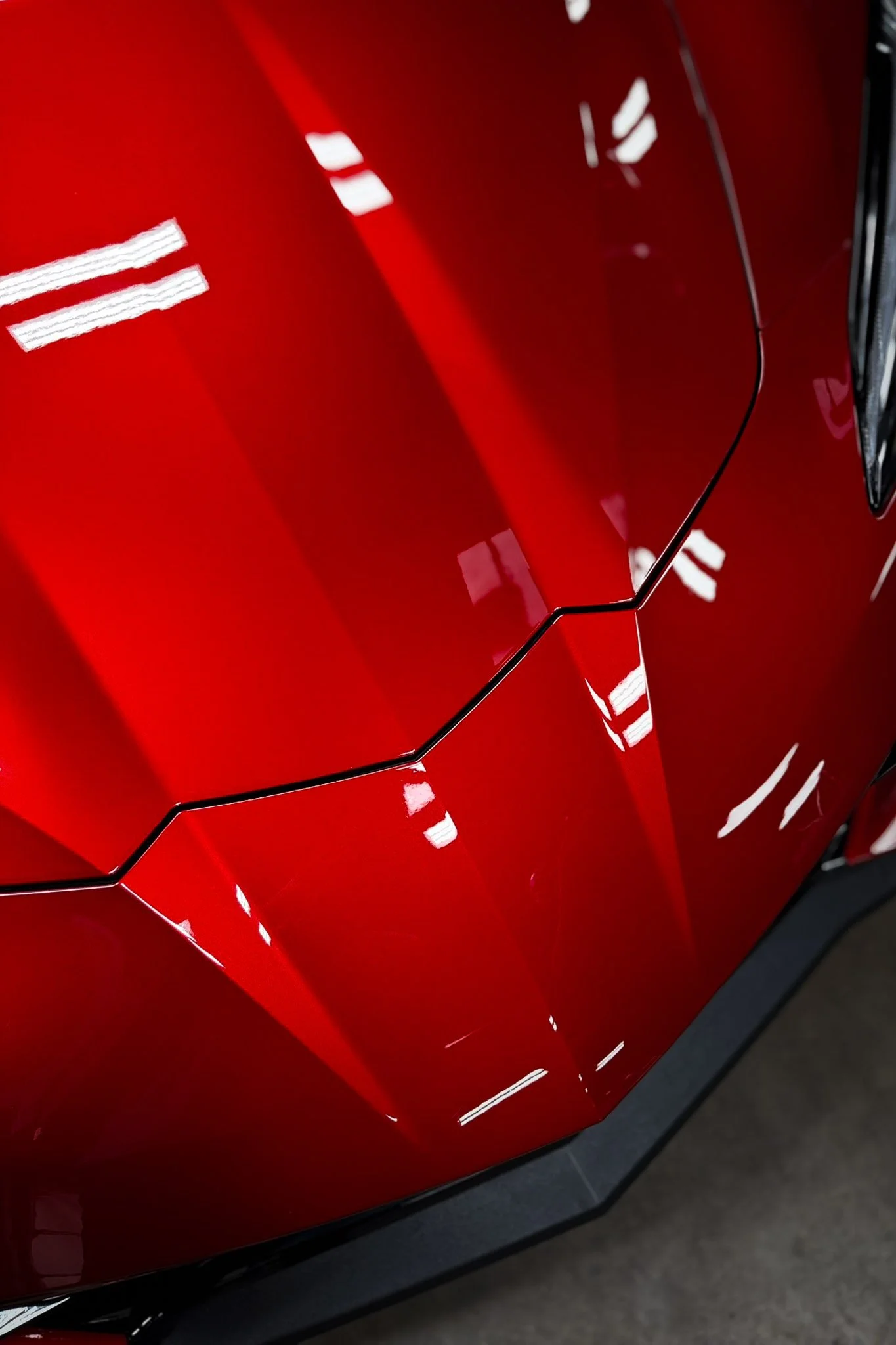 Close-up of the hood on a red sports car showing a precise paint protection film seam - EIGHTYNINE VWS PPF installation in Little Elm, TX
