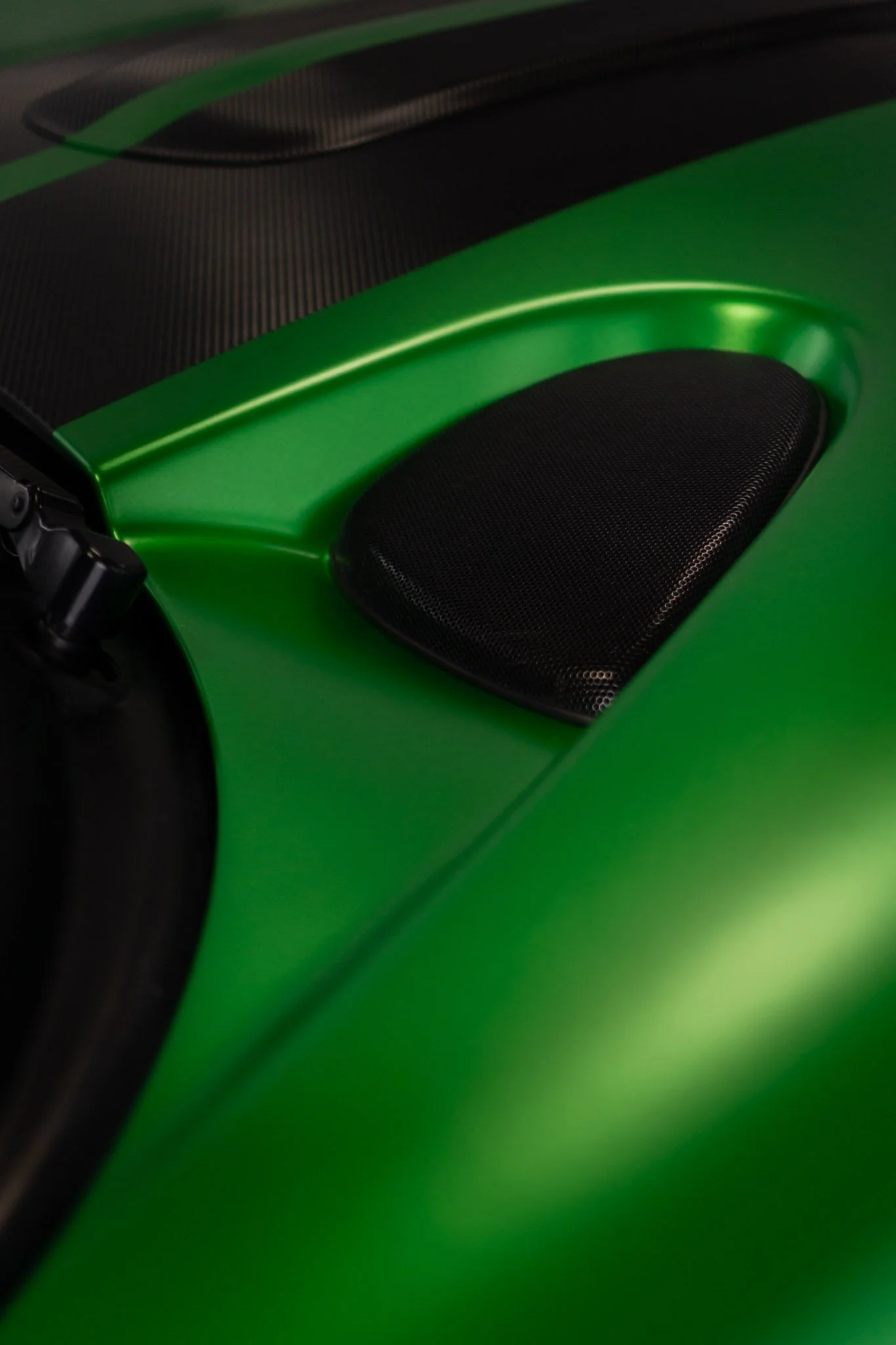 Macro close-up of a glossy emerald green sports car's front fender vent, showing the flawless finish after paint protection film installation by EIGHTYNINE VWS in Little Elm, TX
