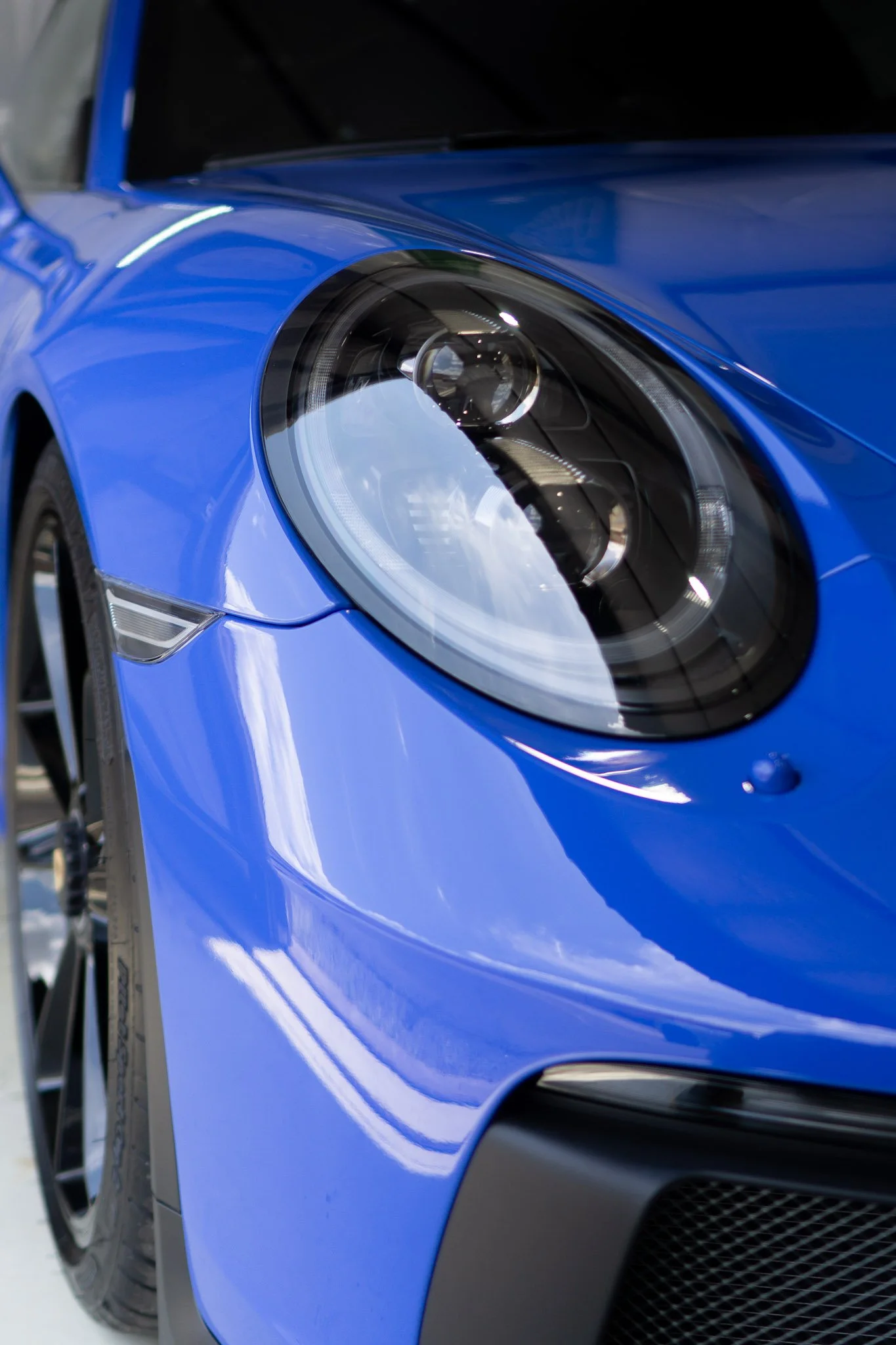 Close-up of a blue Porsche 911's headlight and front fender protected with clear paint protection film - EIGHTYNINE VWS PPF installation in Little Elm, TX