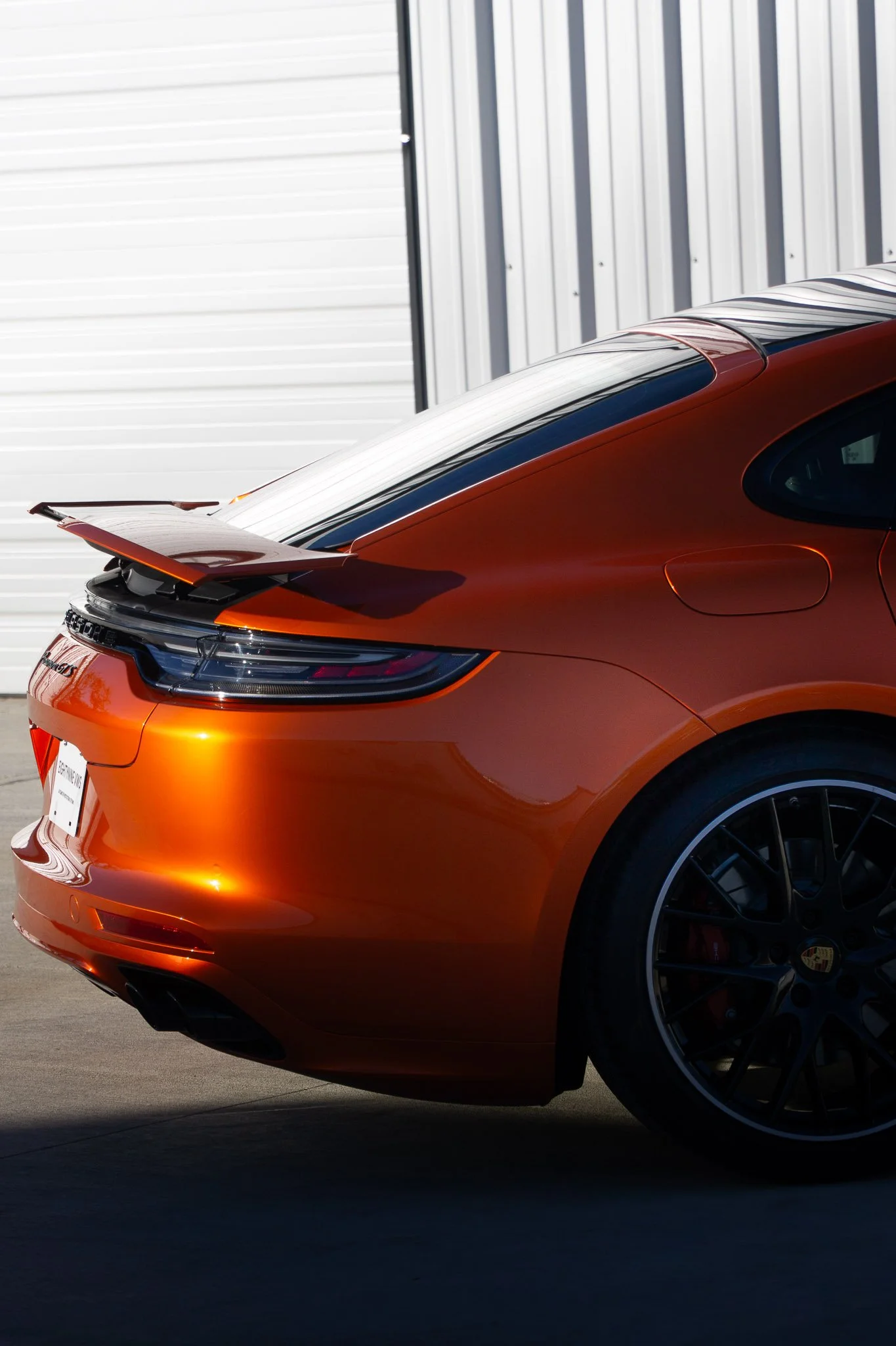 Rear three-quarter view of an orange Porsche 718 Cayman GTS with color change paint protection film, photographed outside EIGHTYNINE VWS's Little Elm, TX studio