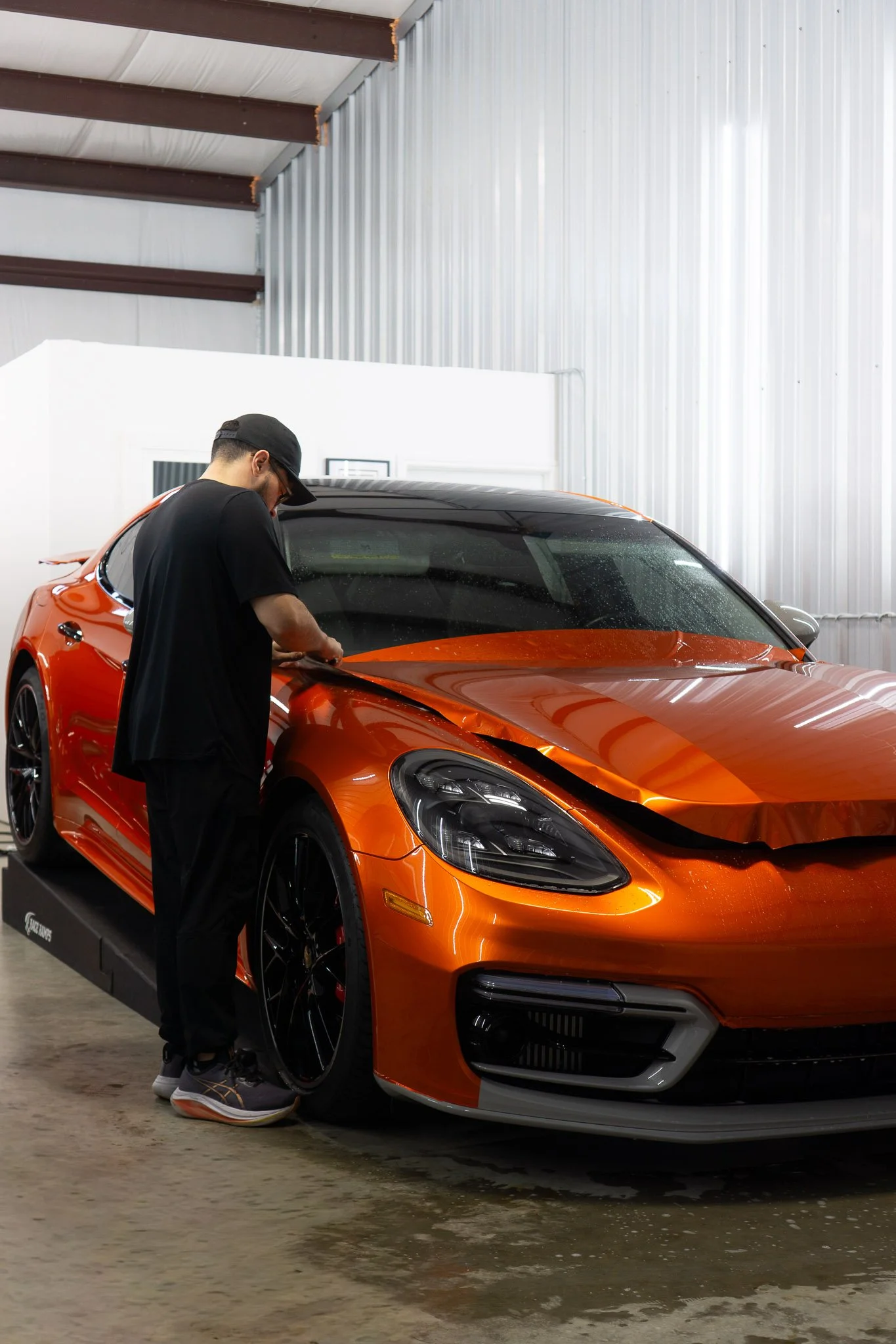 EIGHTYNINE VWS technician inspecting an orange sports coupe wrapped in paint protection film inside the shop garage in Little Elm, TX