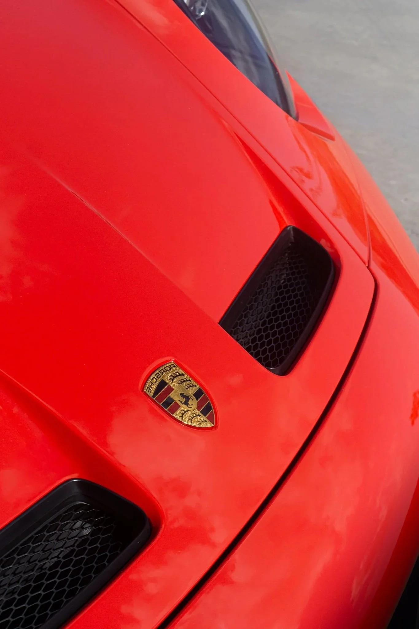Close-up of a red Porsche's side air intake vents with Porsche crest visible, protected by paint protection film - EIGHTYNINE VWS PPF service in Little Elm, TX