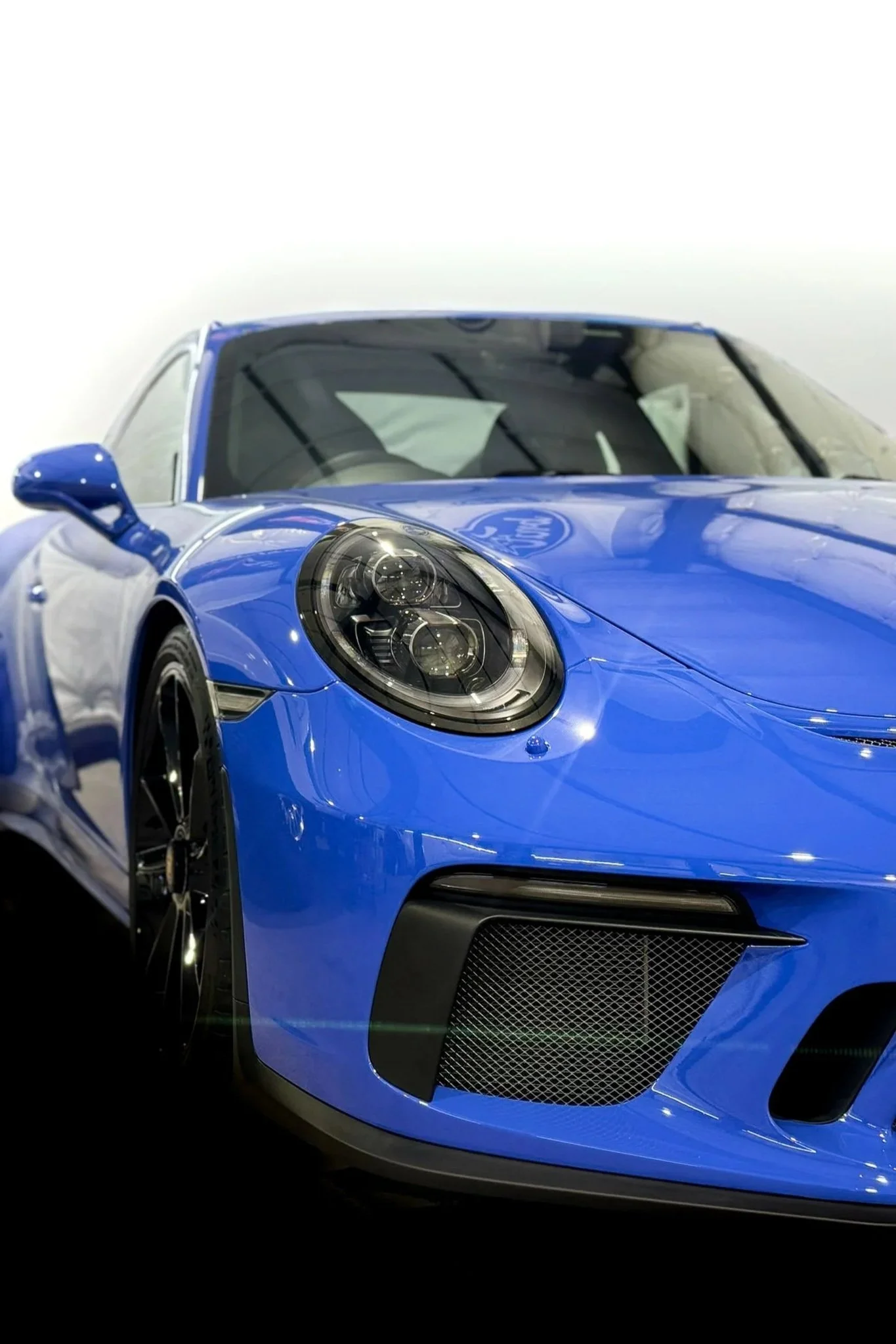 Front bumper and headlight of a blue Porsche 911 sports car with clear paint protection film applied - PPF service by EIGHTYNINE VWS in Little Elm, TX