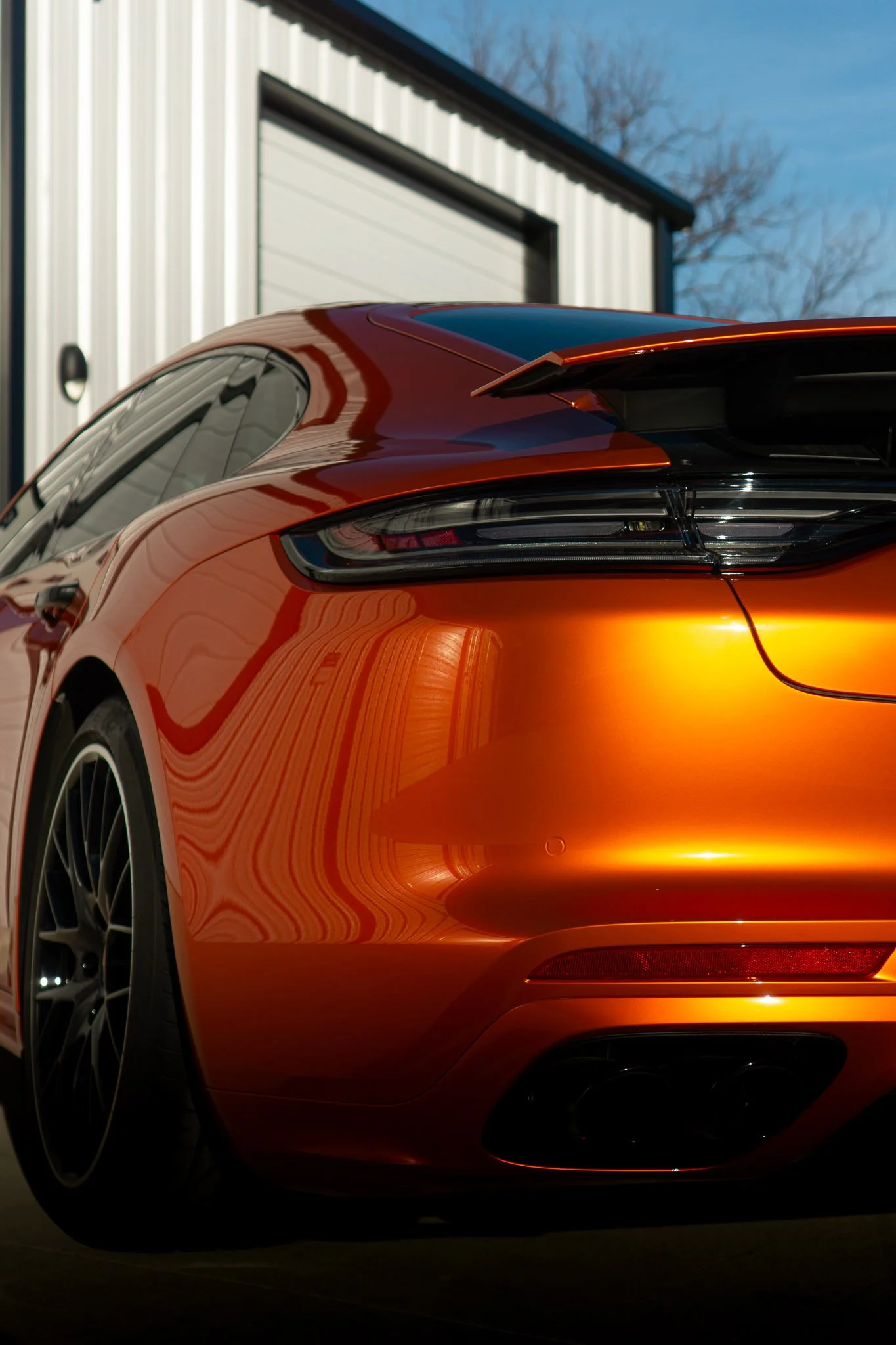 Rear view of an orange Porsche 718 Cayman GTS with color change paint protection film parked outside EIGHTYNINE VWS's Little Elm, TX studio