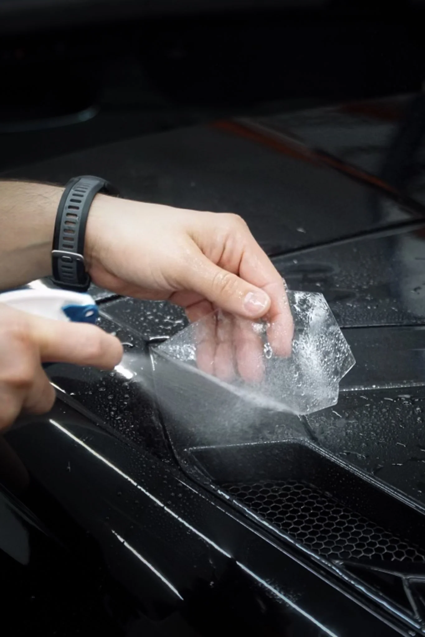 Installer applying slip solution before squeegeeing clear paint protection film onto a vehicle's paint — EIGHTYNINE VWS paint protection film installation, Little Elm, TX.