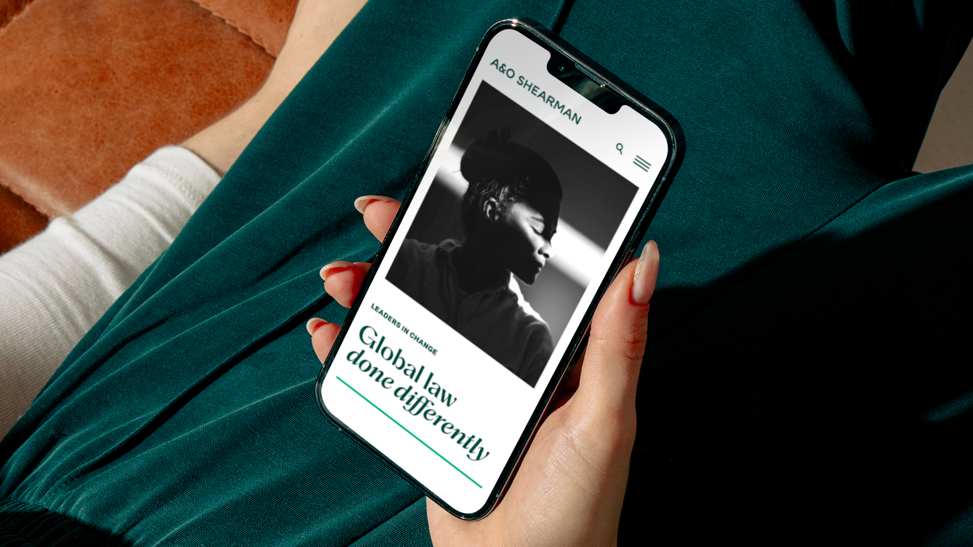 Person holding smartphone with a website displaying a black and white profile photo of a woman and text 'Global law done differently'.