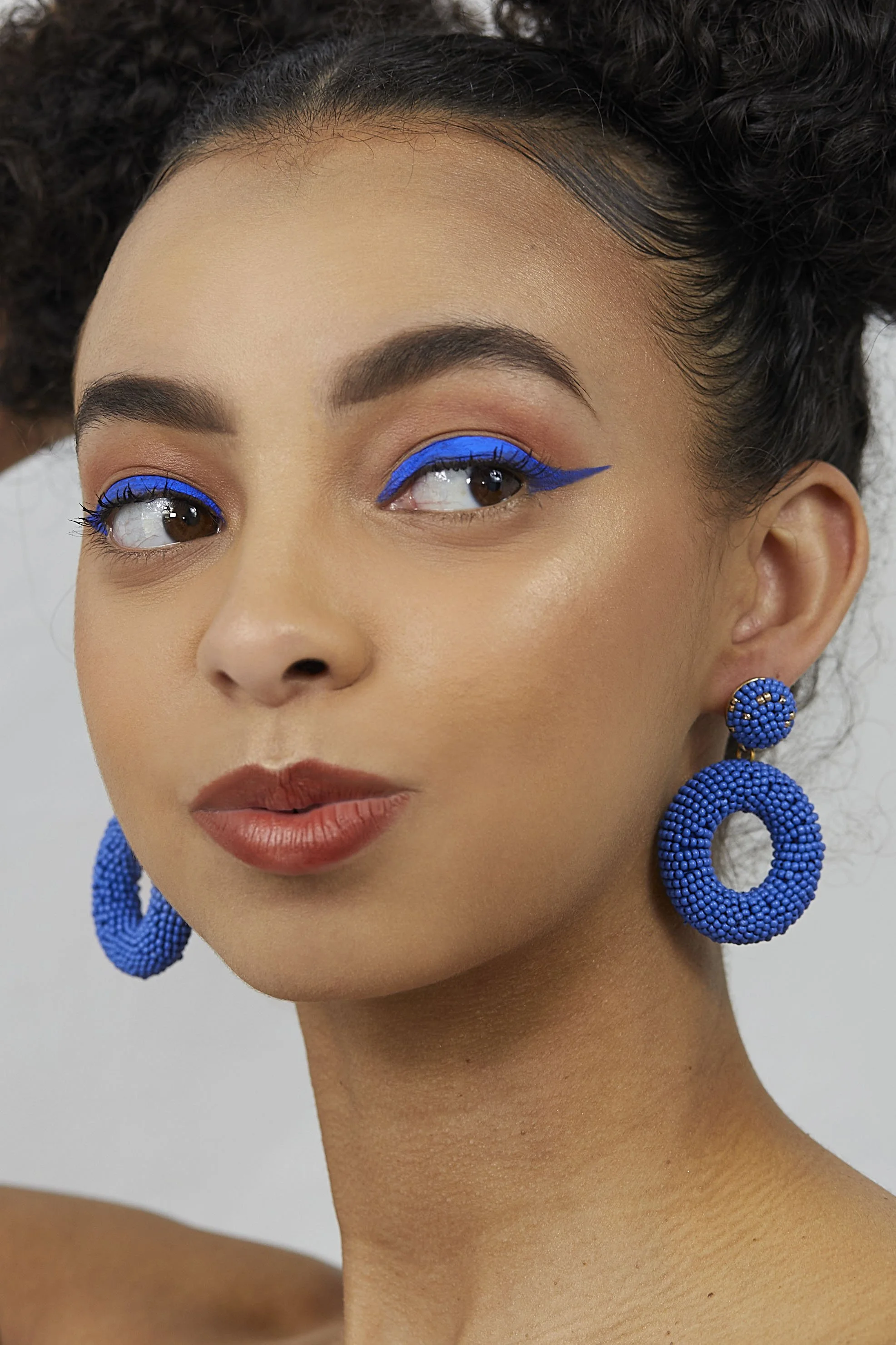 Simple beauty photography, colourful blue make up and jewellery for magazine beauty shoot. Soft natural light beauty shoot by victoria cook photography 