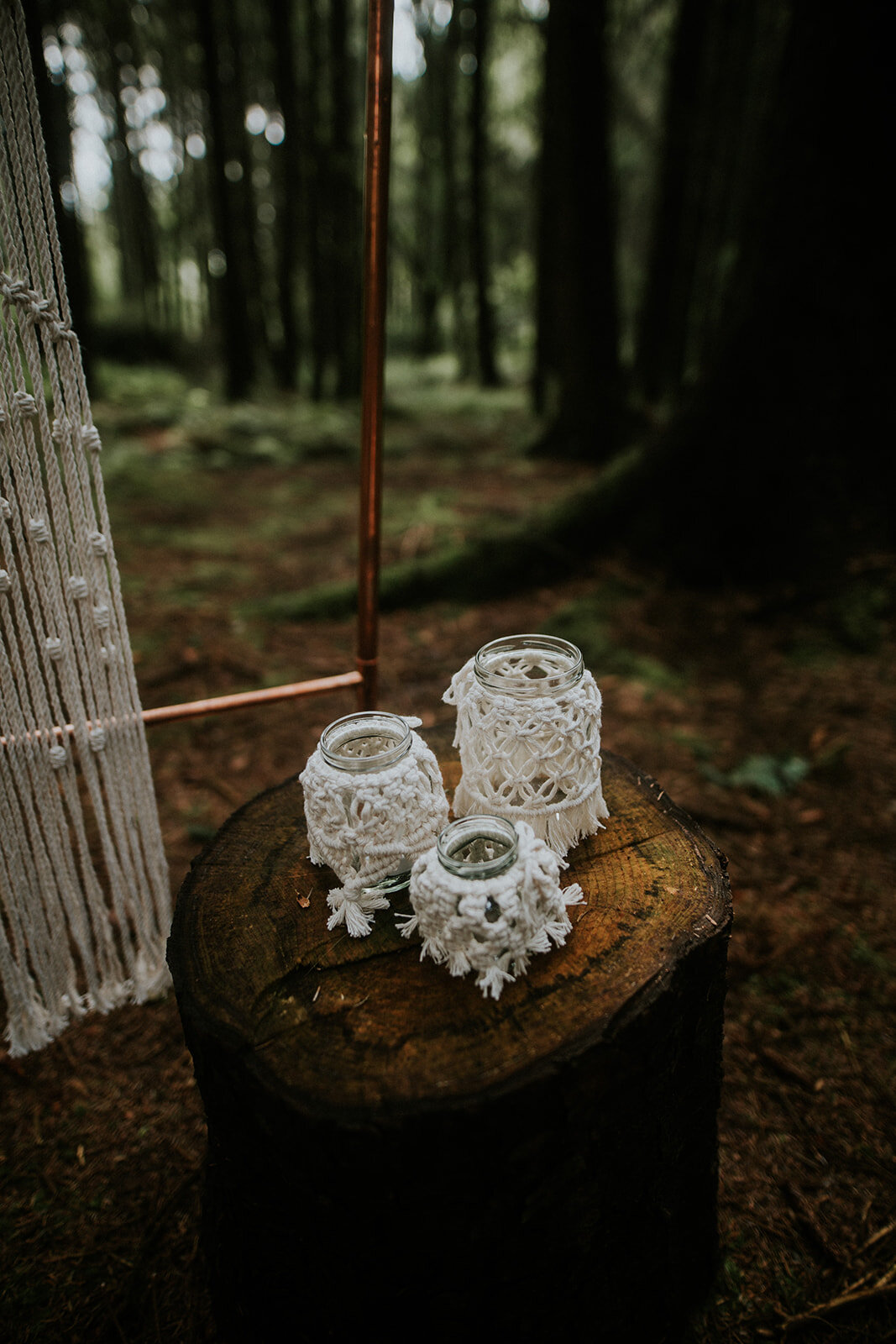 Macrame jars on tree stumps for woodland ceremony