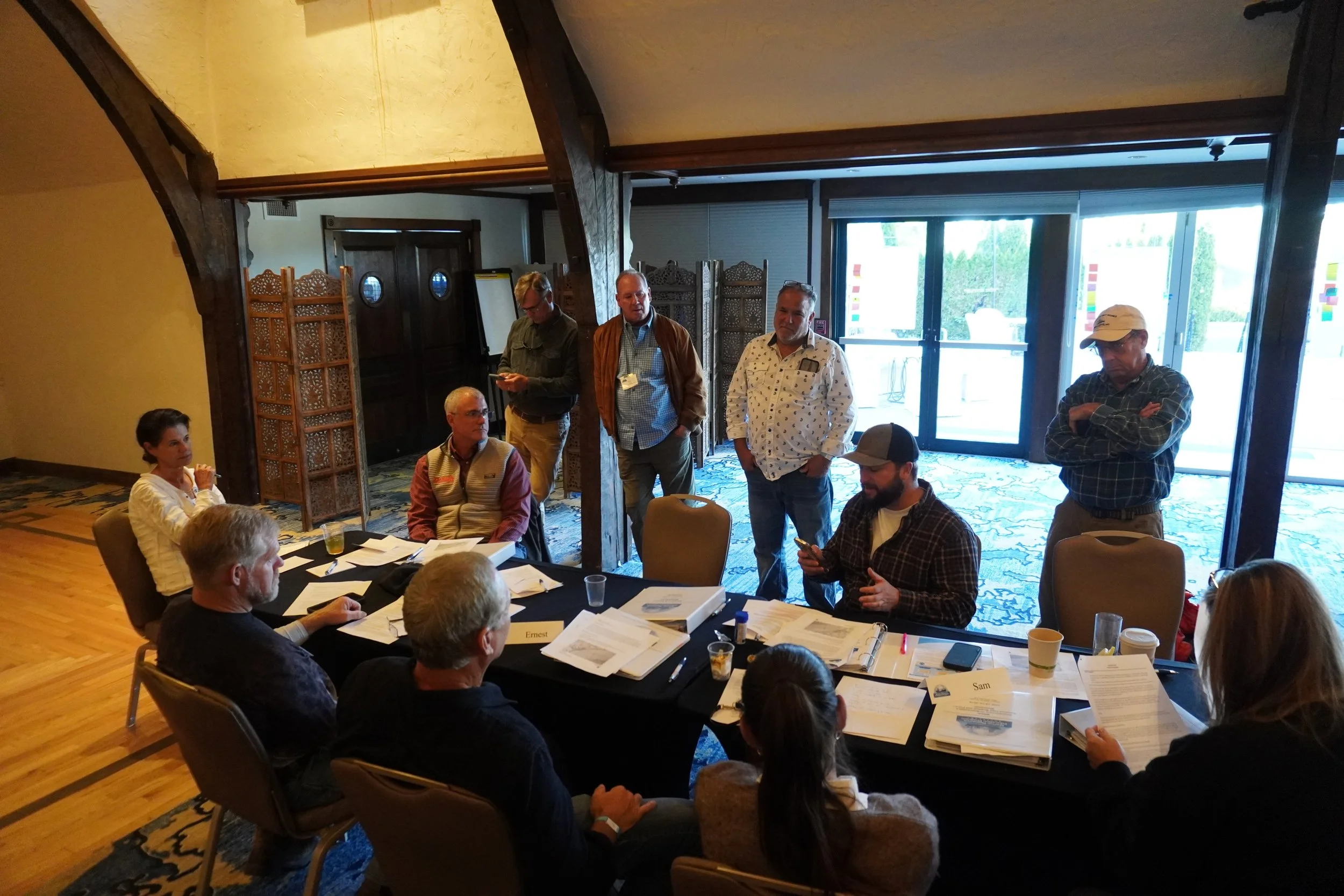 Workshop attendees are talking around a table that is covered with workshop materials