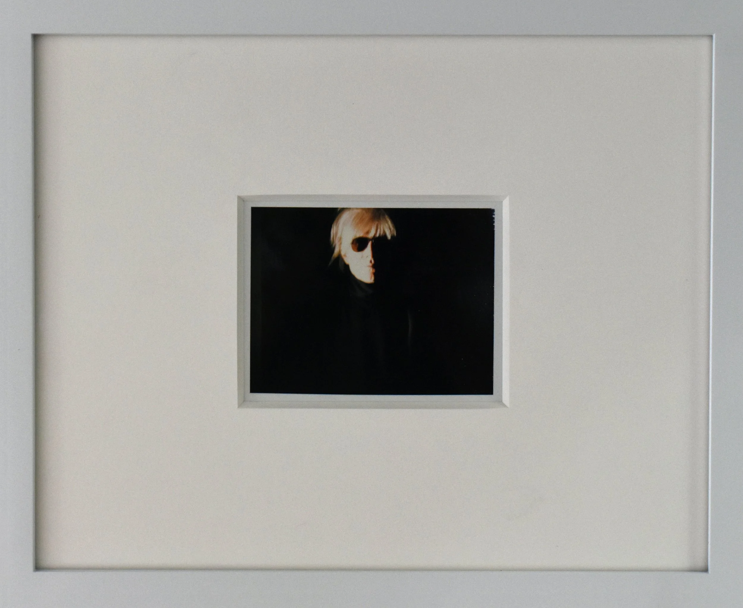 Andy Warhol’s unique Polaroid print, 'Self-Portrait in Fright Wig', shown here in a white frame.