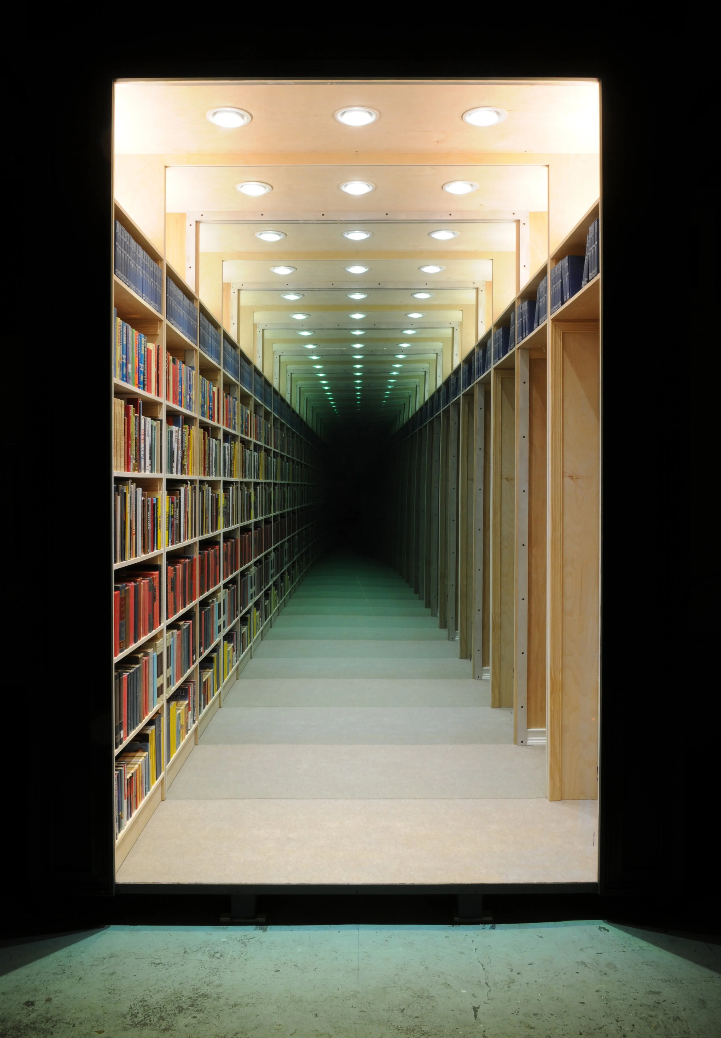 A front facing image of Chul Hyun Ahn’s 2018 work, ‘Library’. The work consists of wood, aluminum, LED lights, books and mirrors.