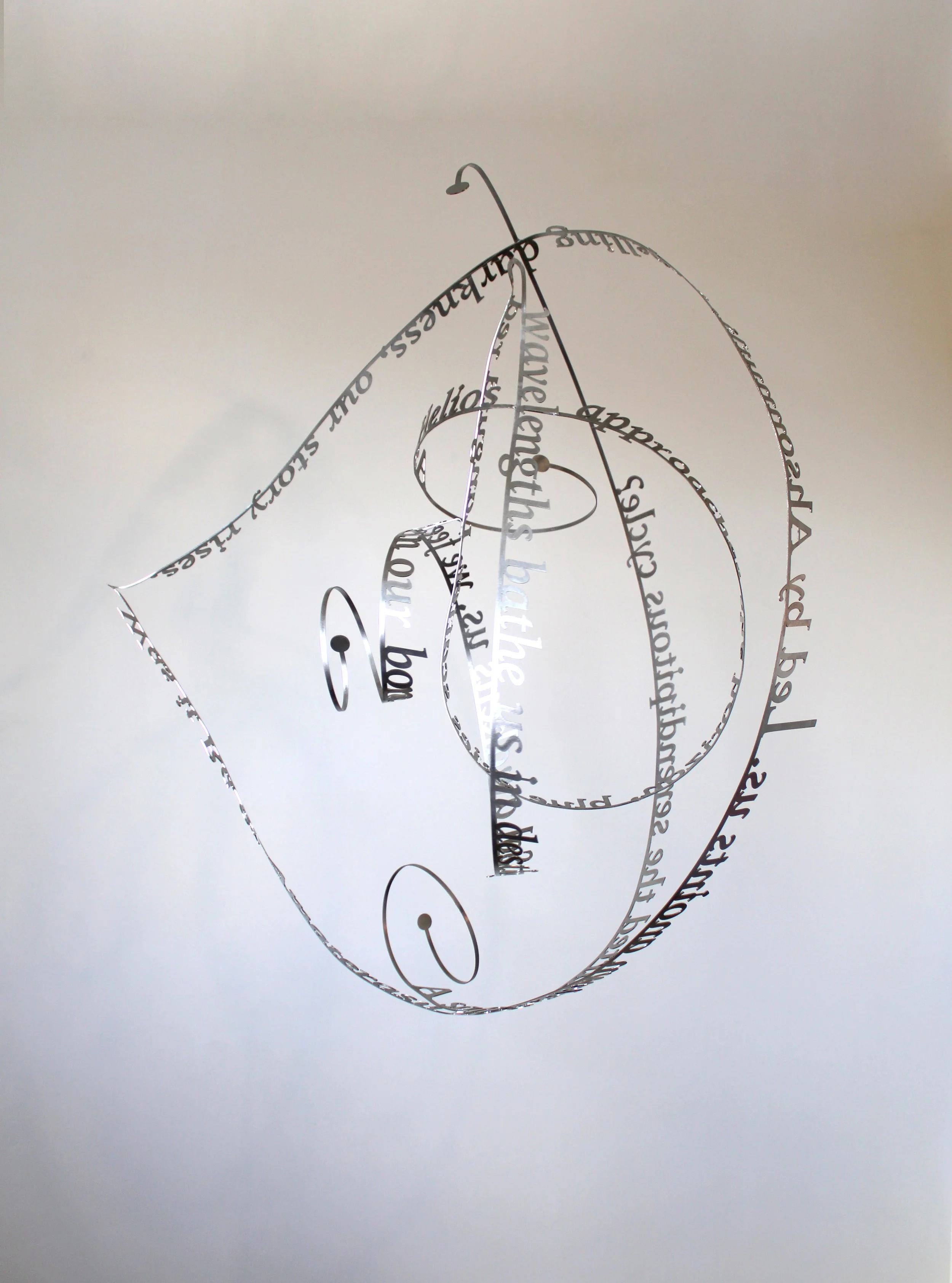 Nicola Anthony’s 'Sun dance', a kinetic stainless steel sculpture. The work is shown here suspended from the ceiling against a white backdrop.