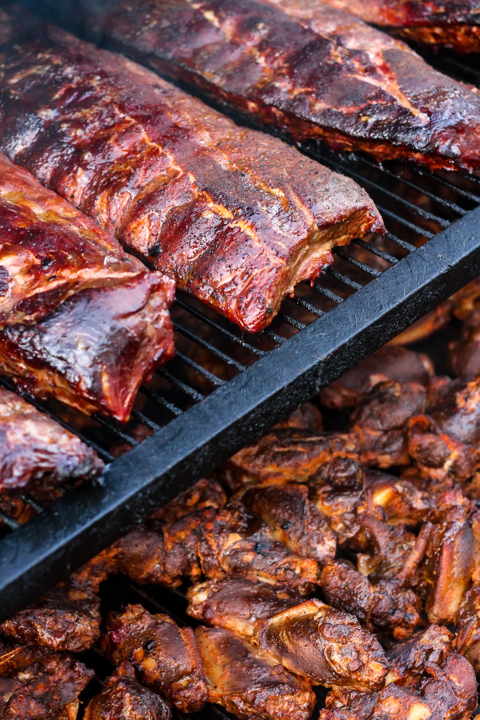 Close-up of barbecued meats, including ribs and chicken, cooked on a grill.