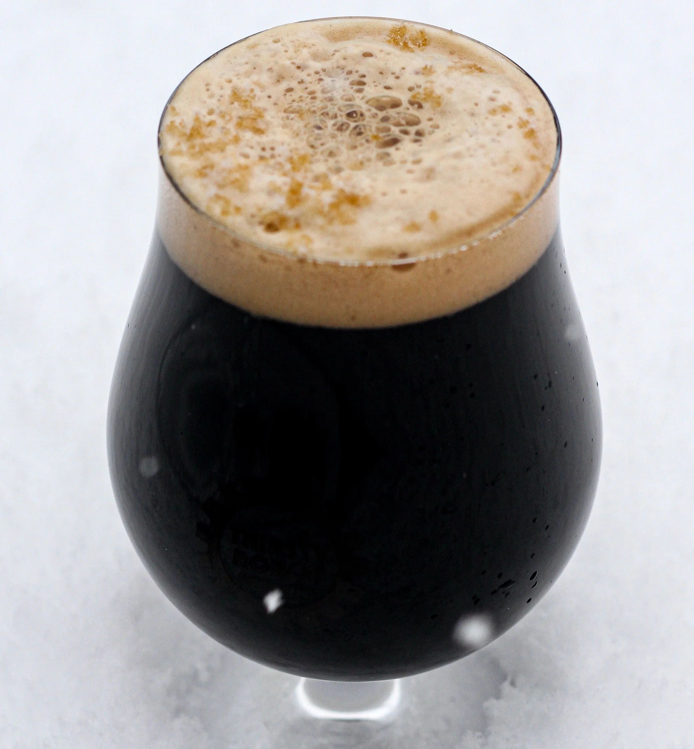 A glass of dark stout beer with a frothy, tan head on top.