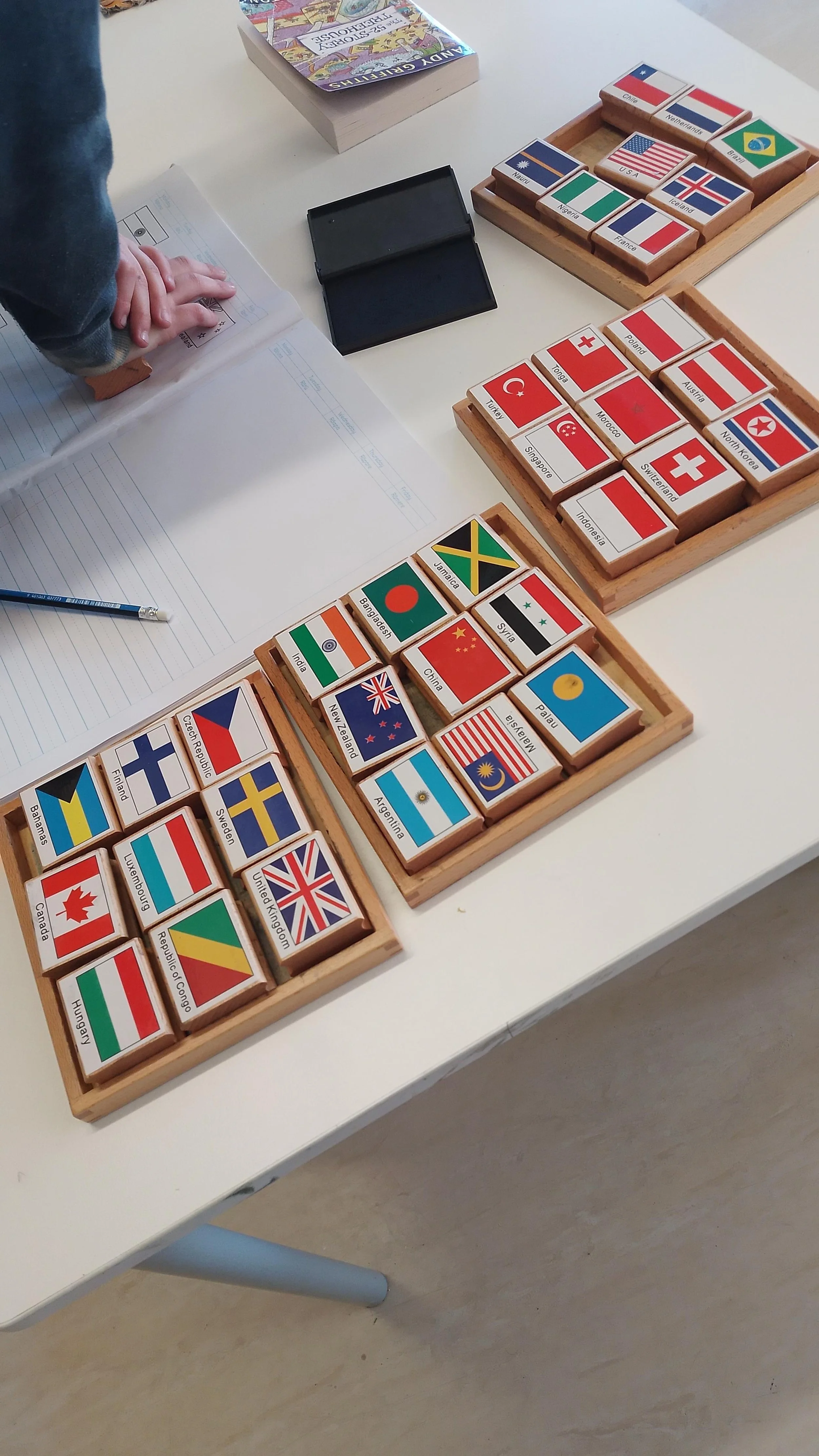 Collection of wooden boxes filled with small rectangular blocks featuring country flags, teaching about the world at porirua montessori  school in wellington