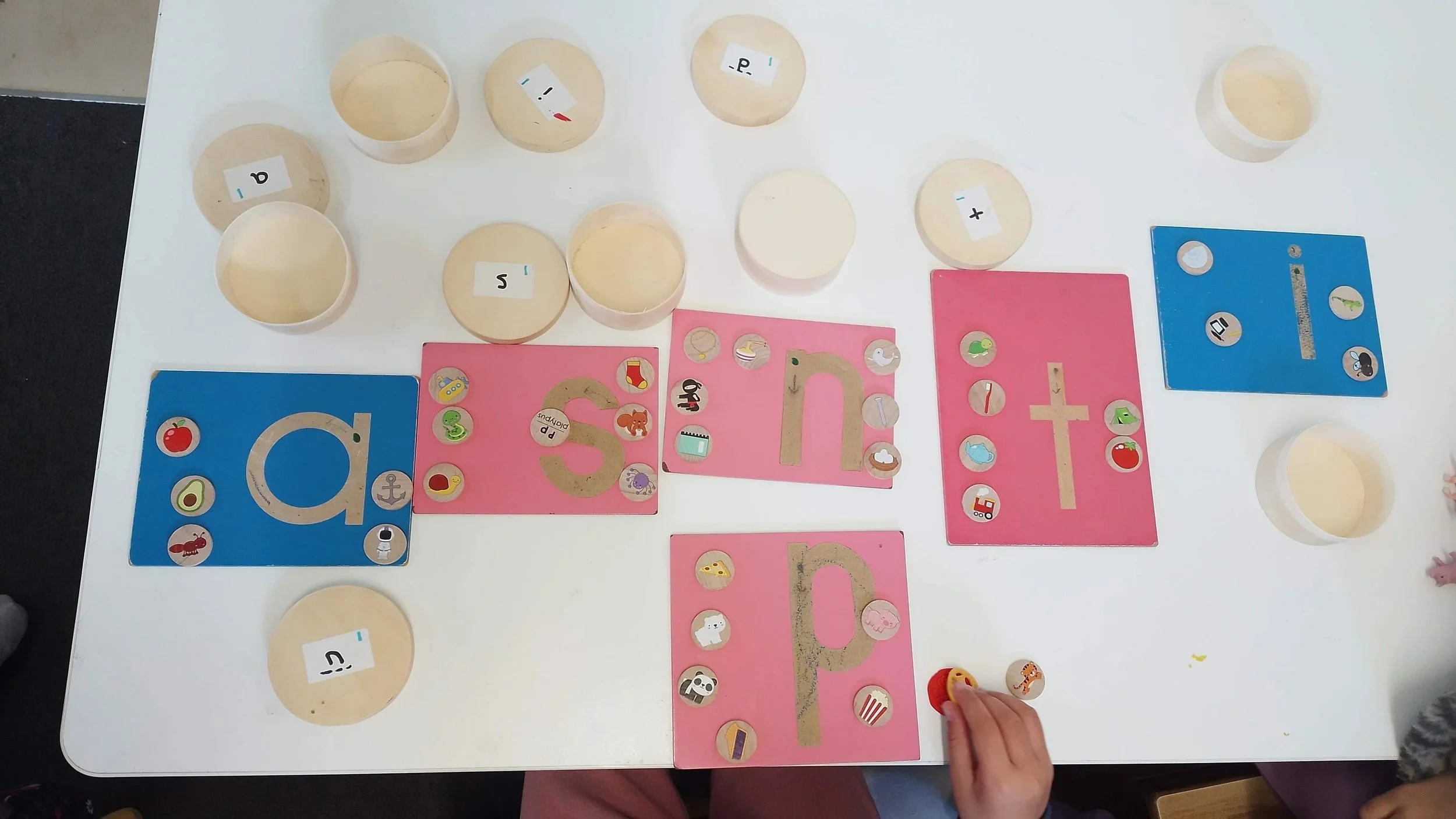 Table with sandpaper letters where teachers matc objects to sound, structured literacy in montessori