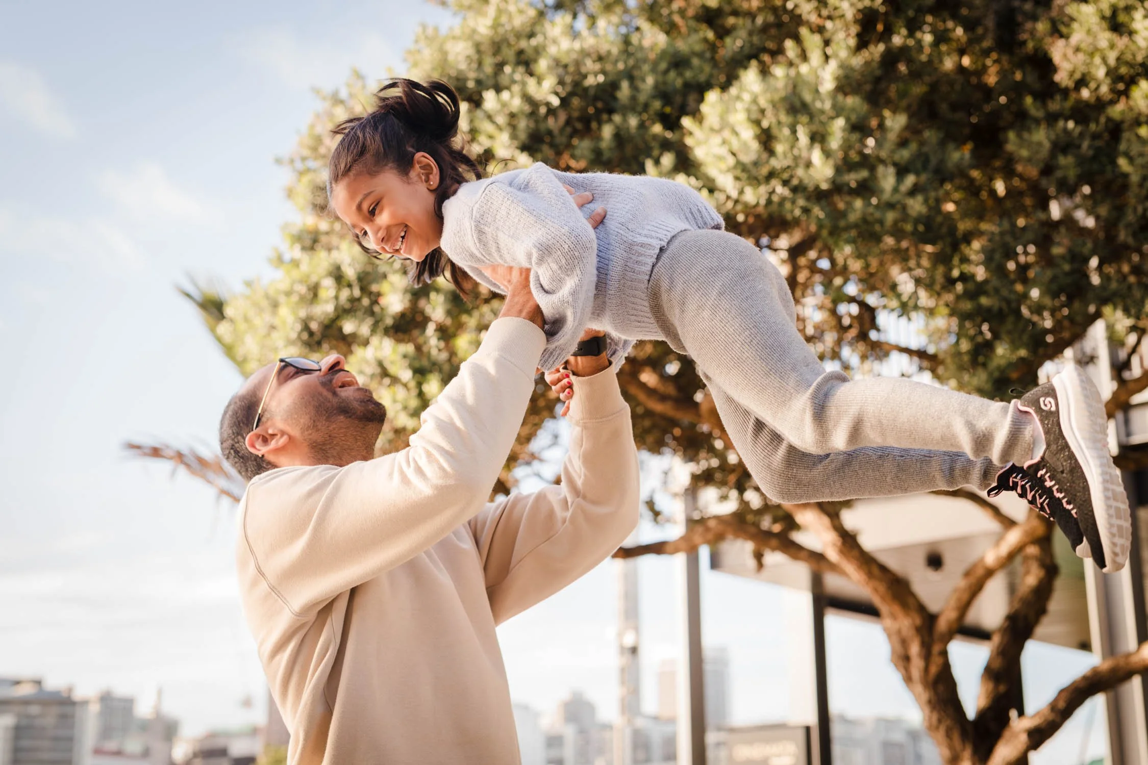 father lifting up his daughter up in the air during their family photography session in Auckland