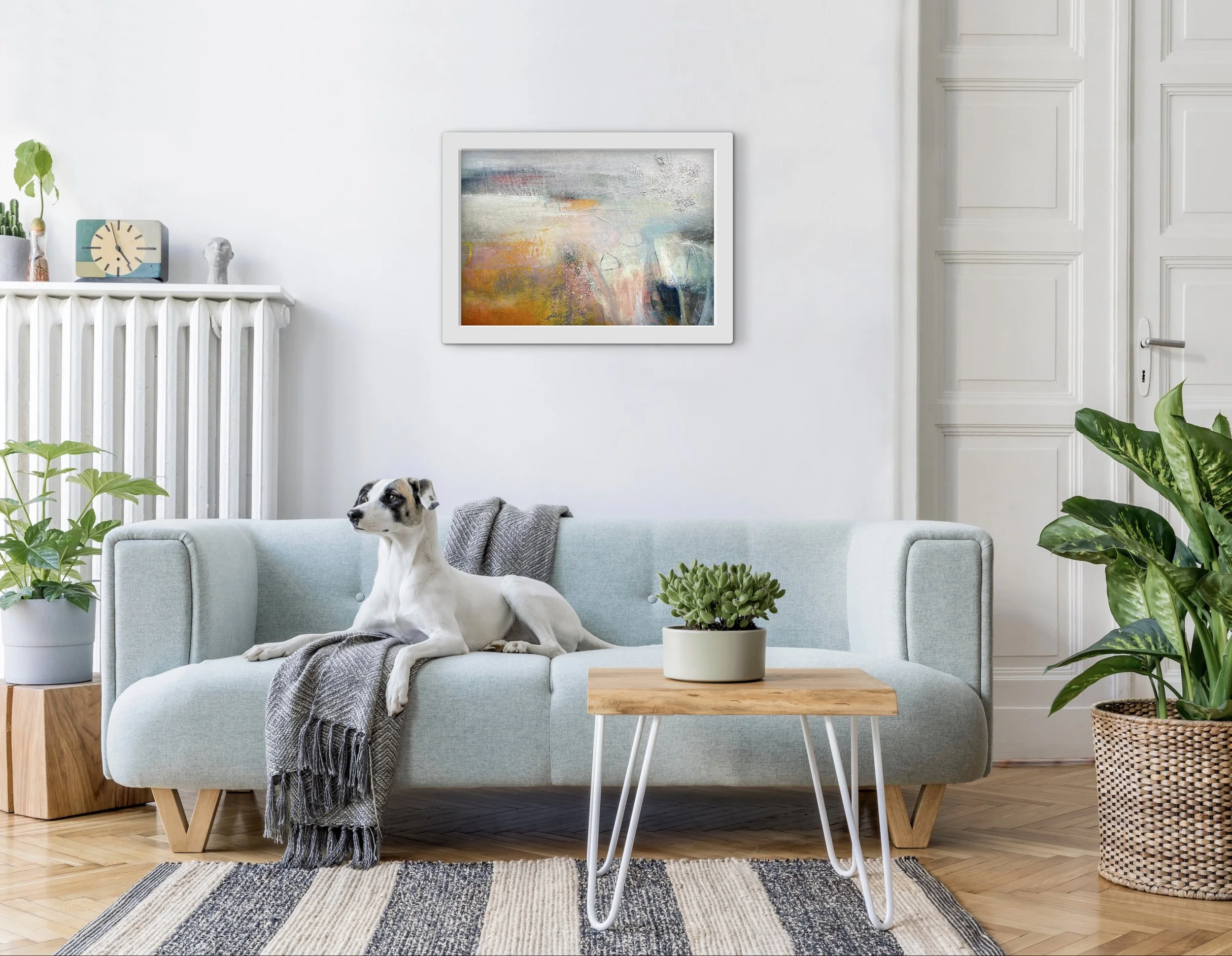 textured abstract landscape with orange and pink accents hung on a white wall