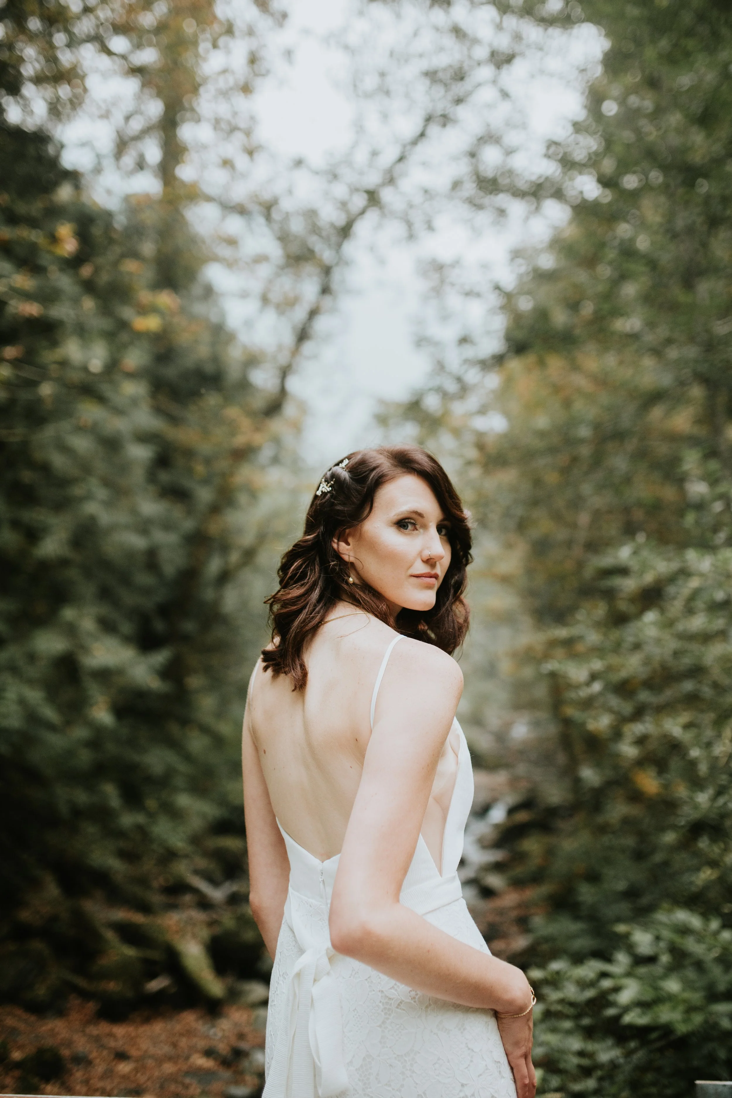 Bride in a white lace dress in a forest setting