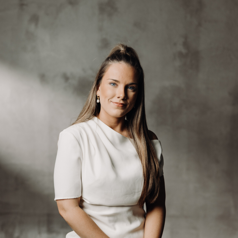 Amelia Nankervis, Buyers Agent at The Srama Group in a suit and dress shirt against a vine-covered brick wall