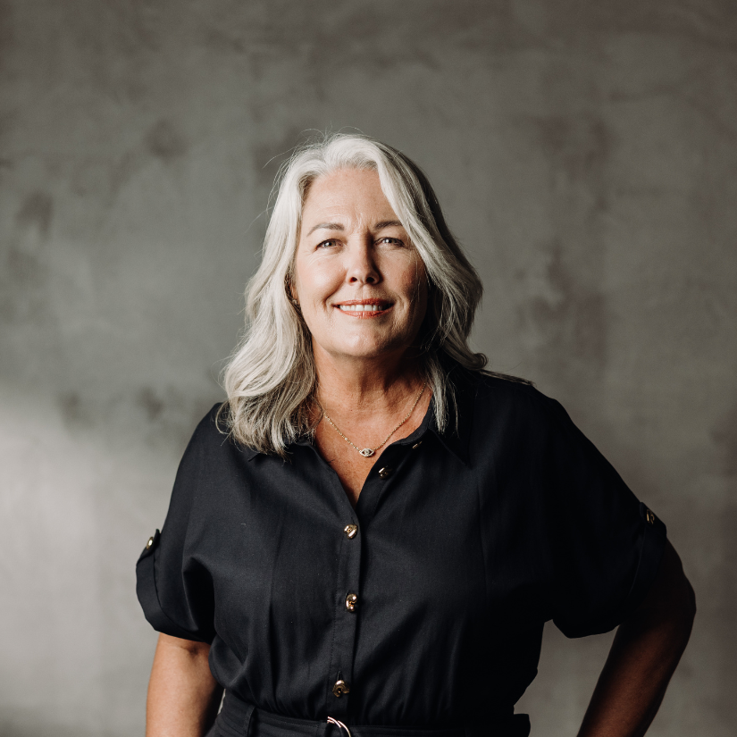 JacquiForrester, Buyers Agent at The Srama Group in a suit and dress shirt against a vine-covered brick wall