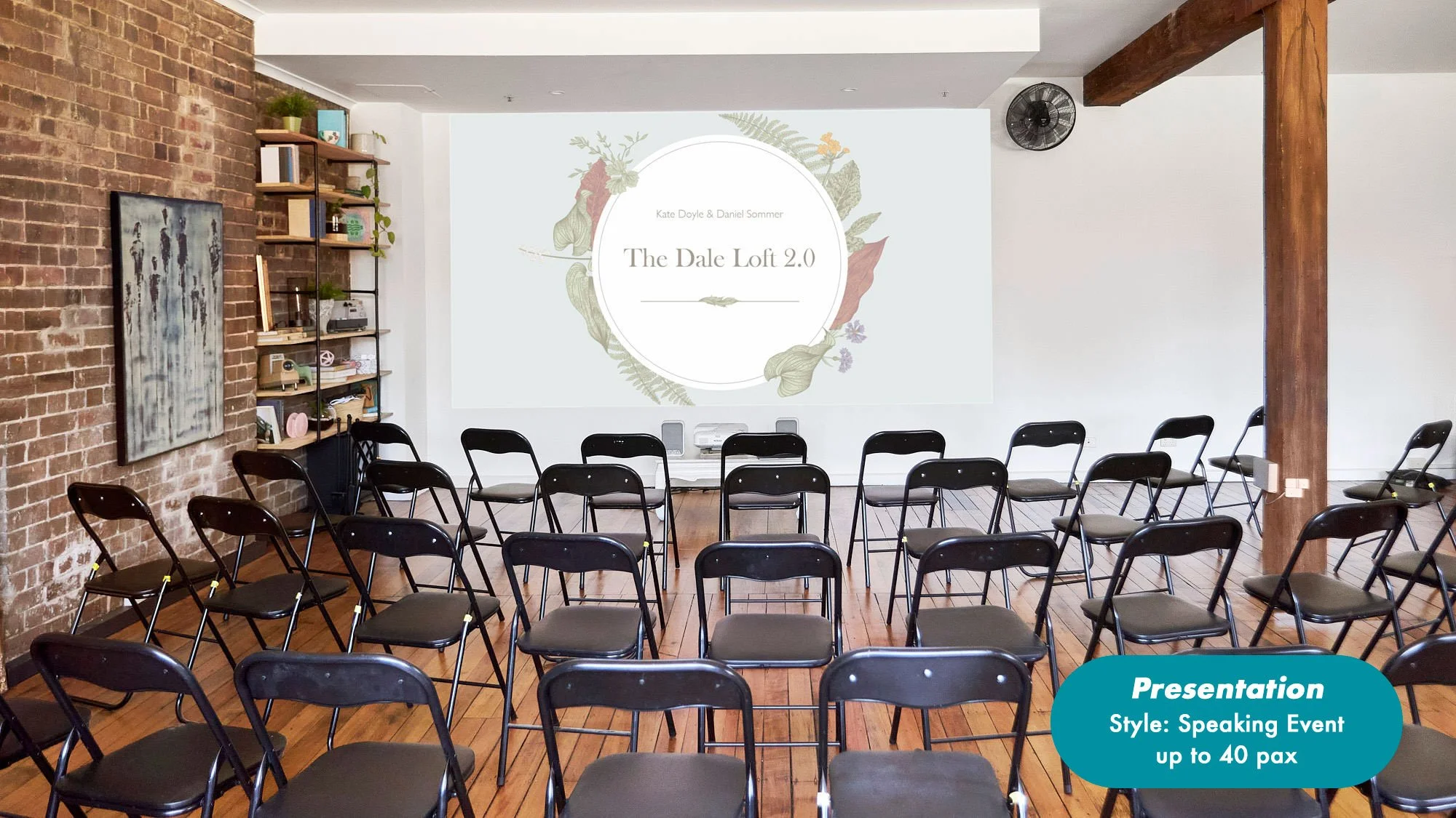 Event venue arranged with rows of black folding chairs, brick walls, wooden beams, and a presentation screen labeled "The Dale Loft 2.0."