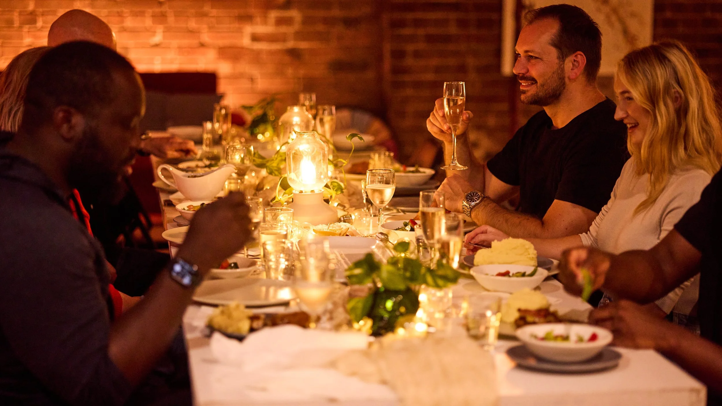 Friends enjoying a candlelit dinner together at a large table at the Dale Studio in Chippendale. 