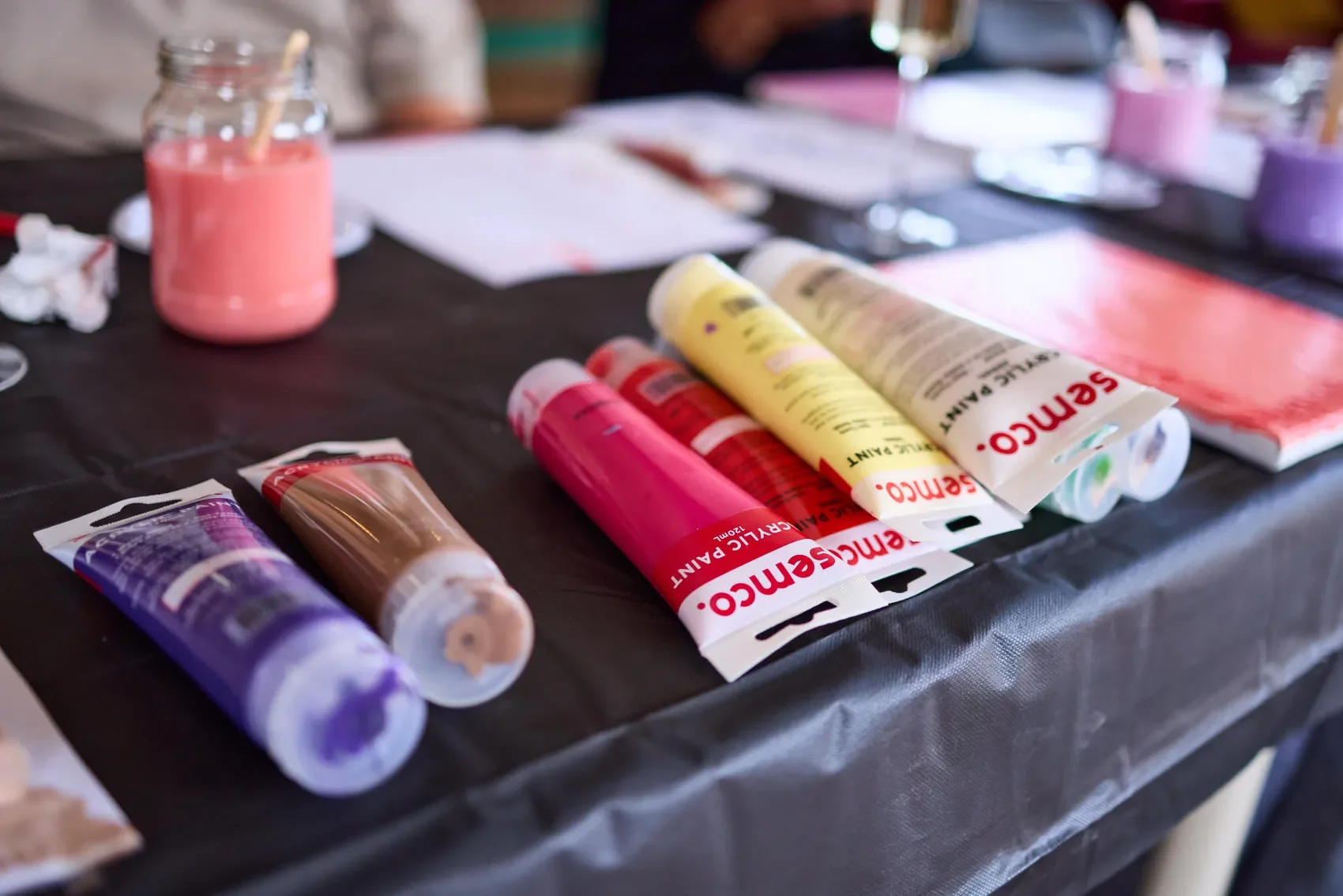 Assorted colorful acrylic paint tubes and a jar of pink paint on a table at the Dale Library in Chippendale. 