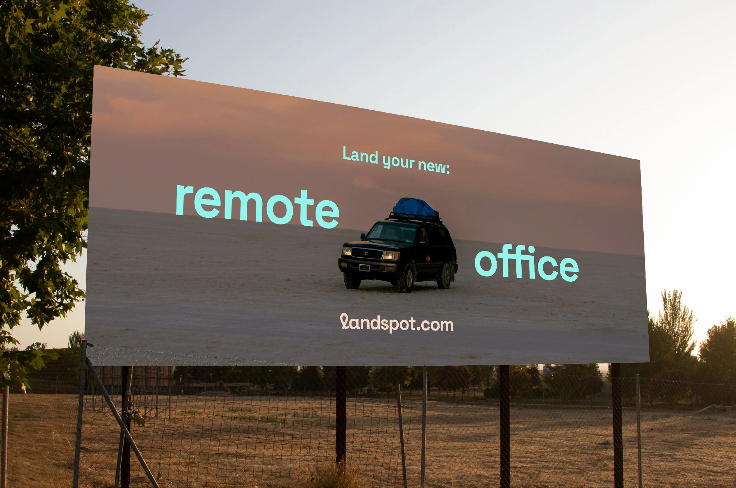 Billboard advertising land for a remote office, featuring a vehicle on a desert landscape at sunset.