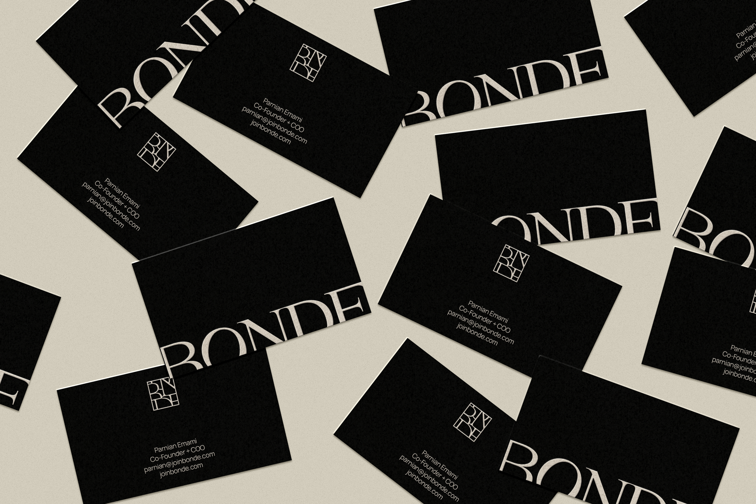 Multiple black business cards with white text and logo scattered on a light surface, displaying the name 'BONDE' and contact information for Parían Emami.
