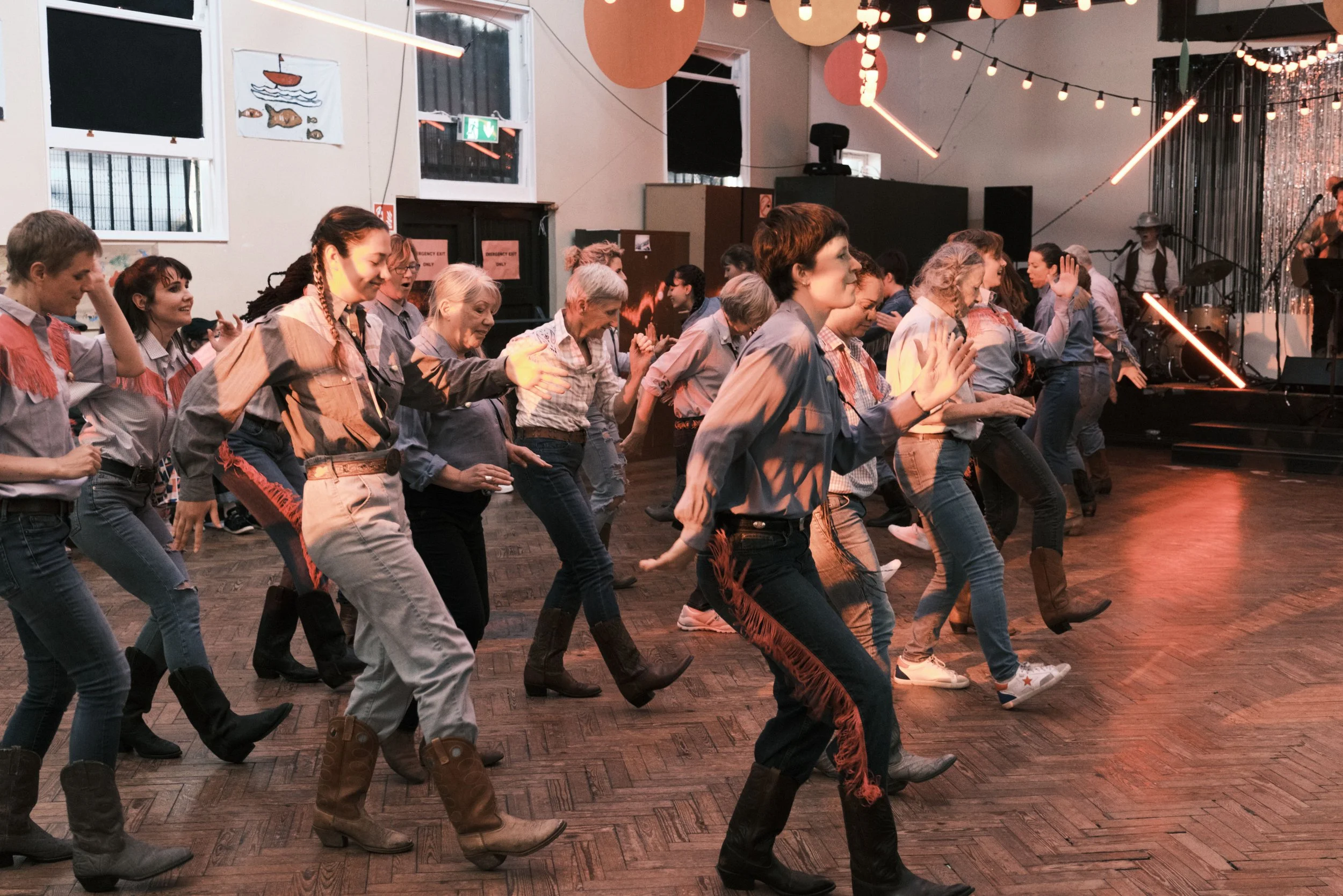 A group of people dressed in cowboy costumes dancing to a live band. Image by Zé Bateira