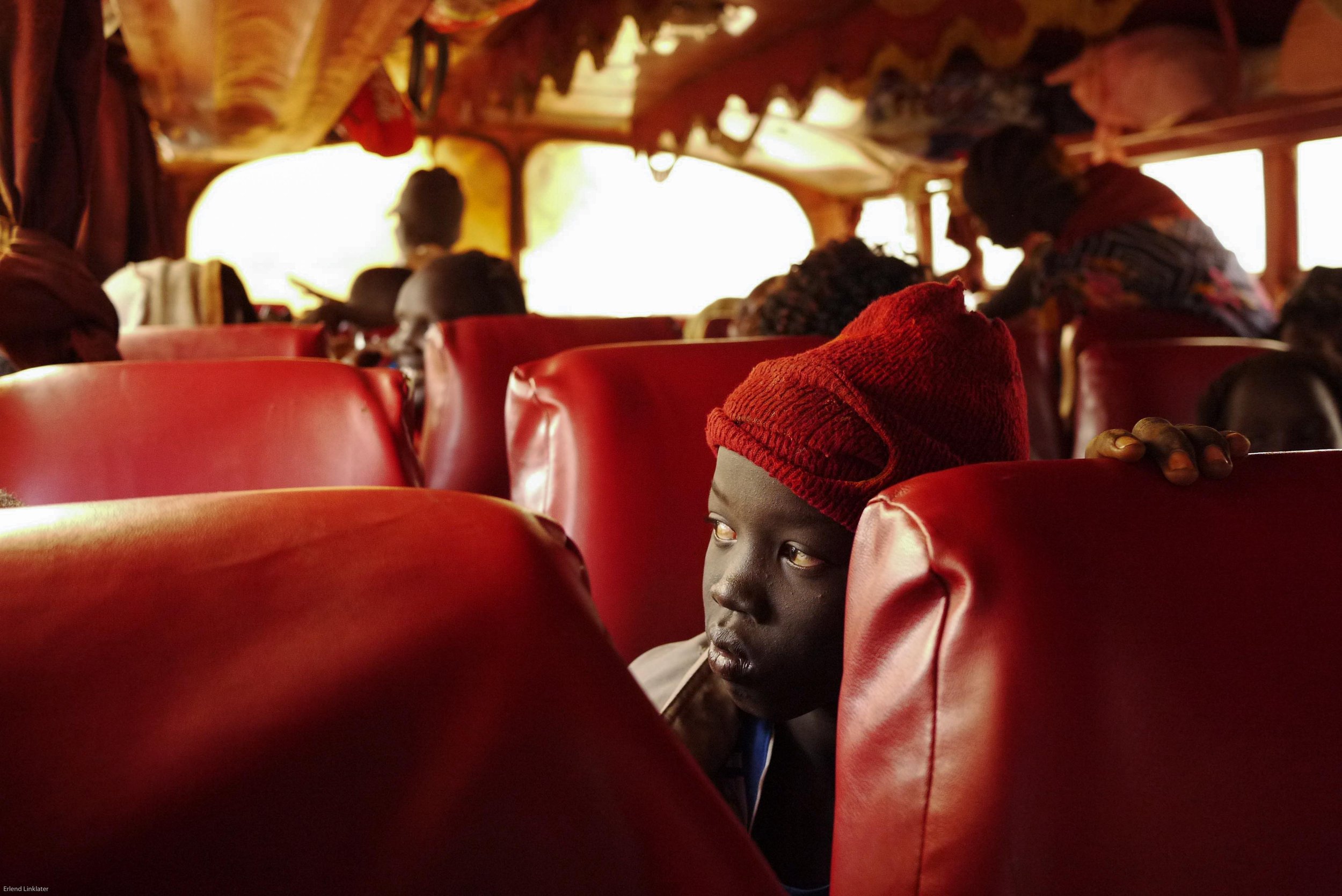 A returning young refugee peers tentatively out of the bus that has brought him back to his parents' homeland. After more than 30 years of conflict, the Comprehensive Peace Agreement and independence referendum has meant that refugees who had fled s