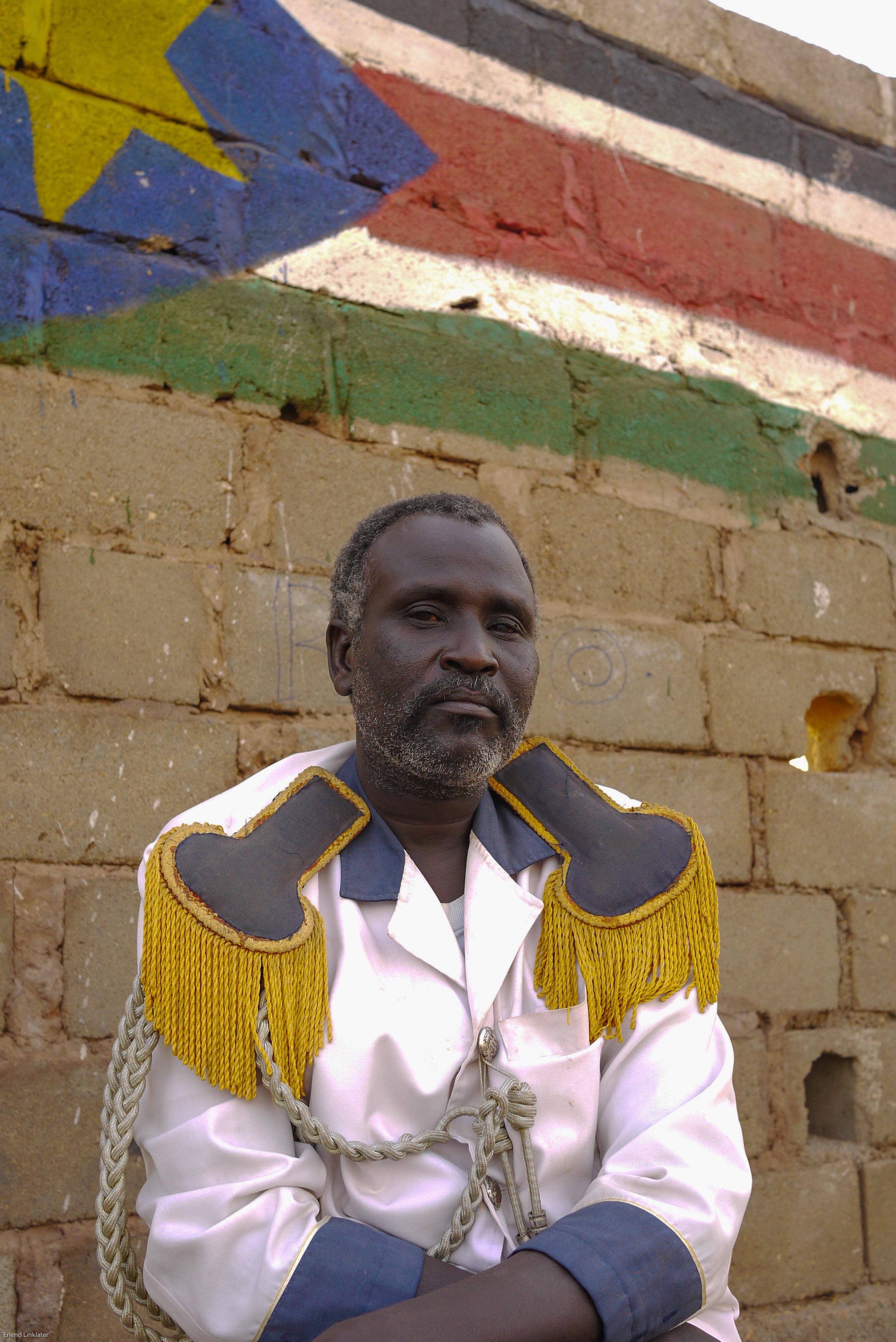 A band member takes a rest from ceremonial duties, Bentiu 2011. Above him is painted the proposed flag of the newly independent South Sudan.