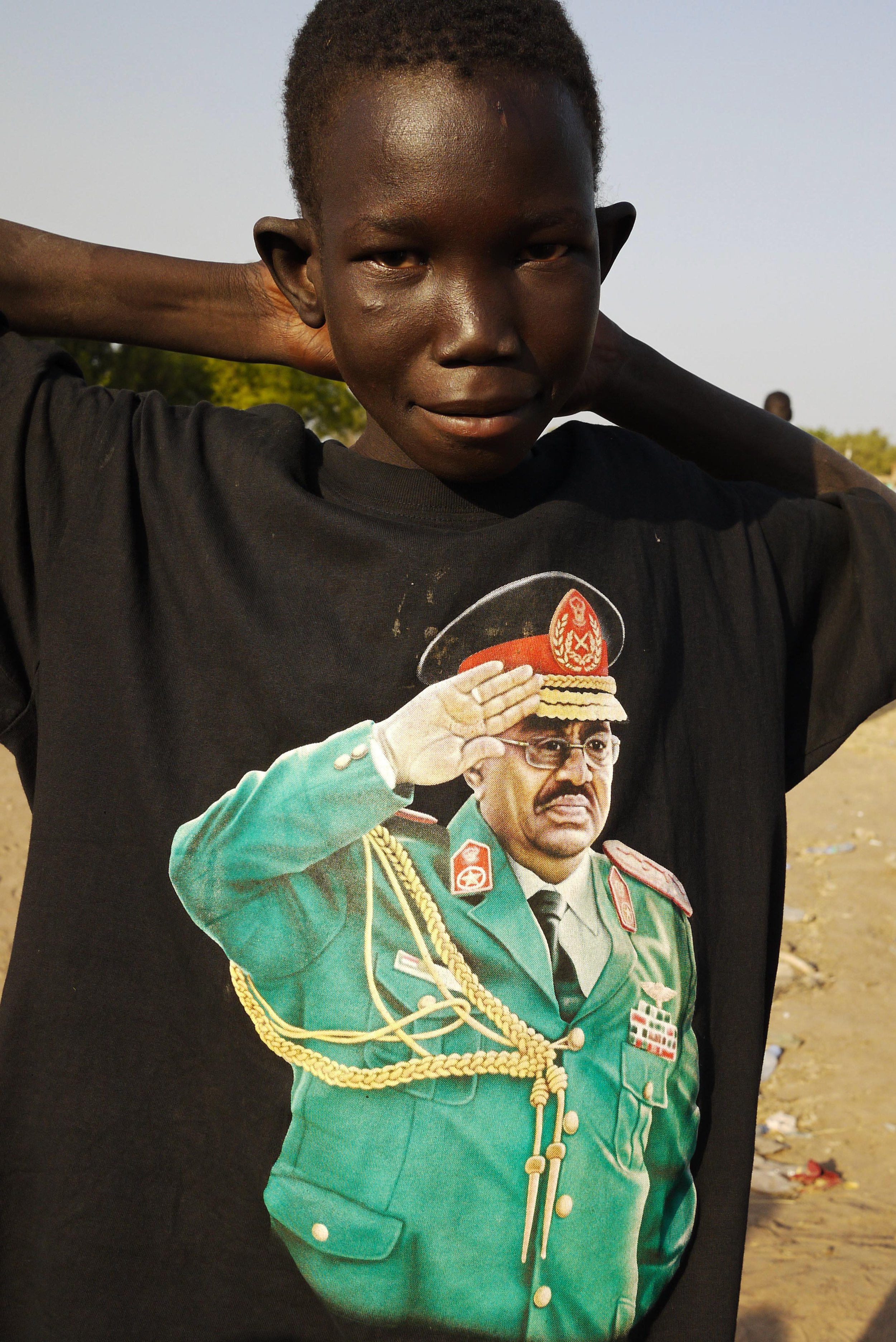 A refugee recently returned to South Sudan from Khartoum wears a t-shirt featuring Sudan president Omar al-Bashir in military uniform. Seizing power in a coup d’etat in 1989 al-Bashir ruled Sudan with an iron fist. He had deep links with the various