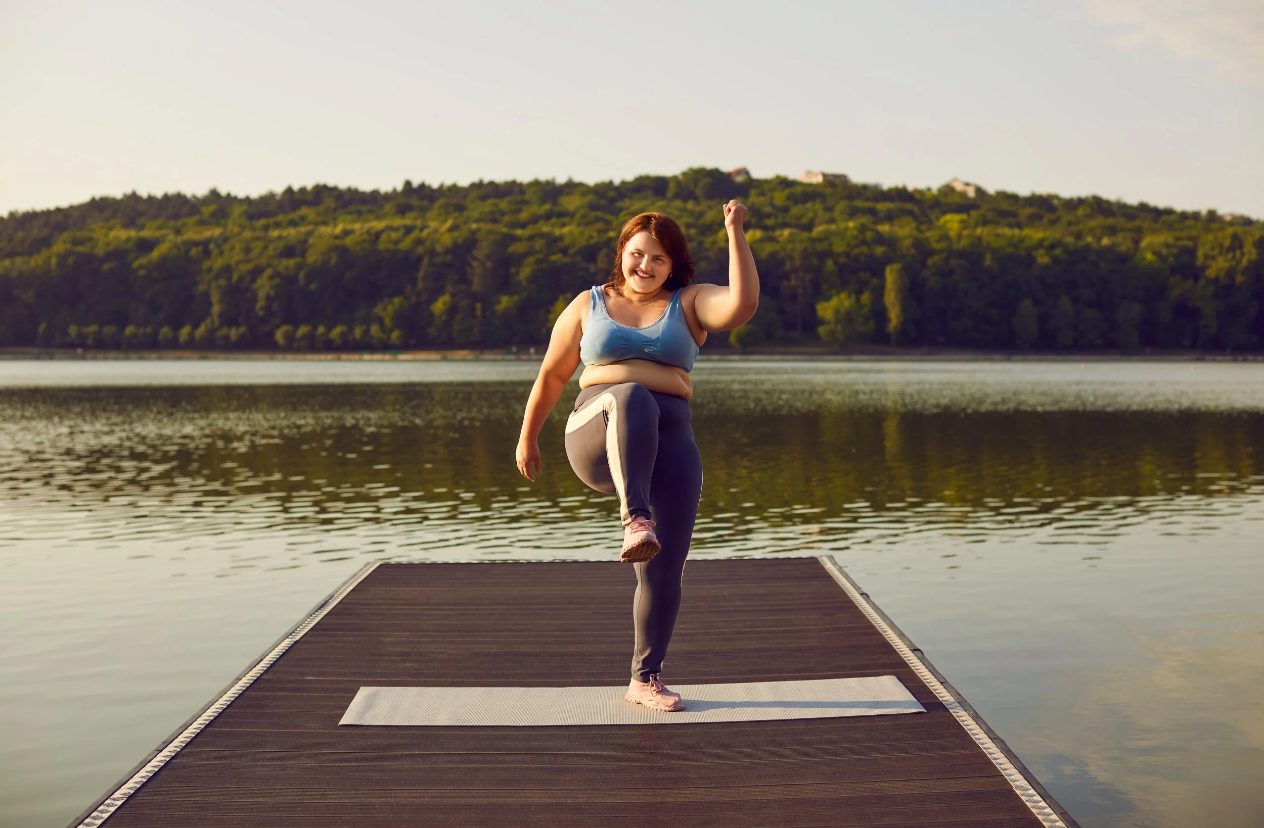woman exercises on a pier near a lake