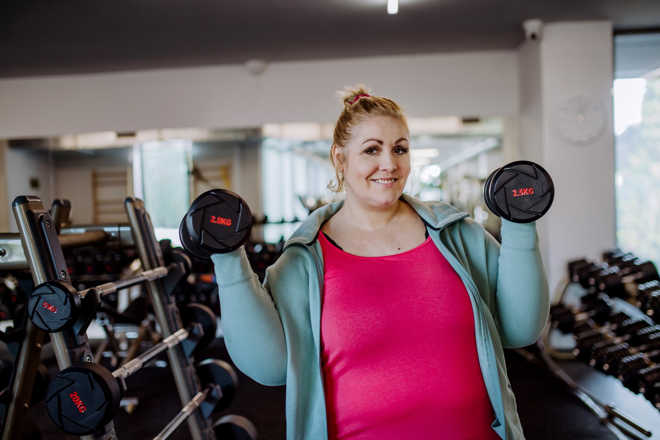 fat blonde woman lifting weights at the gym