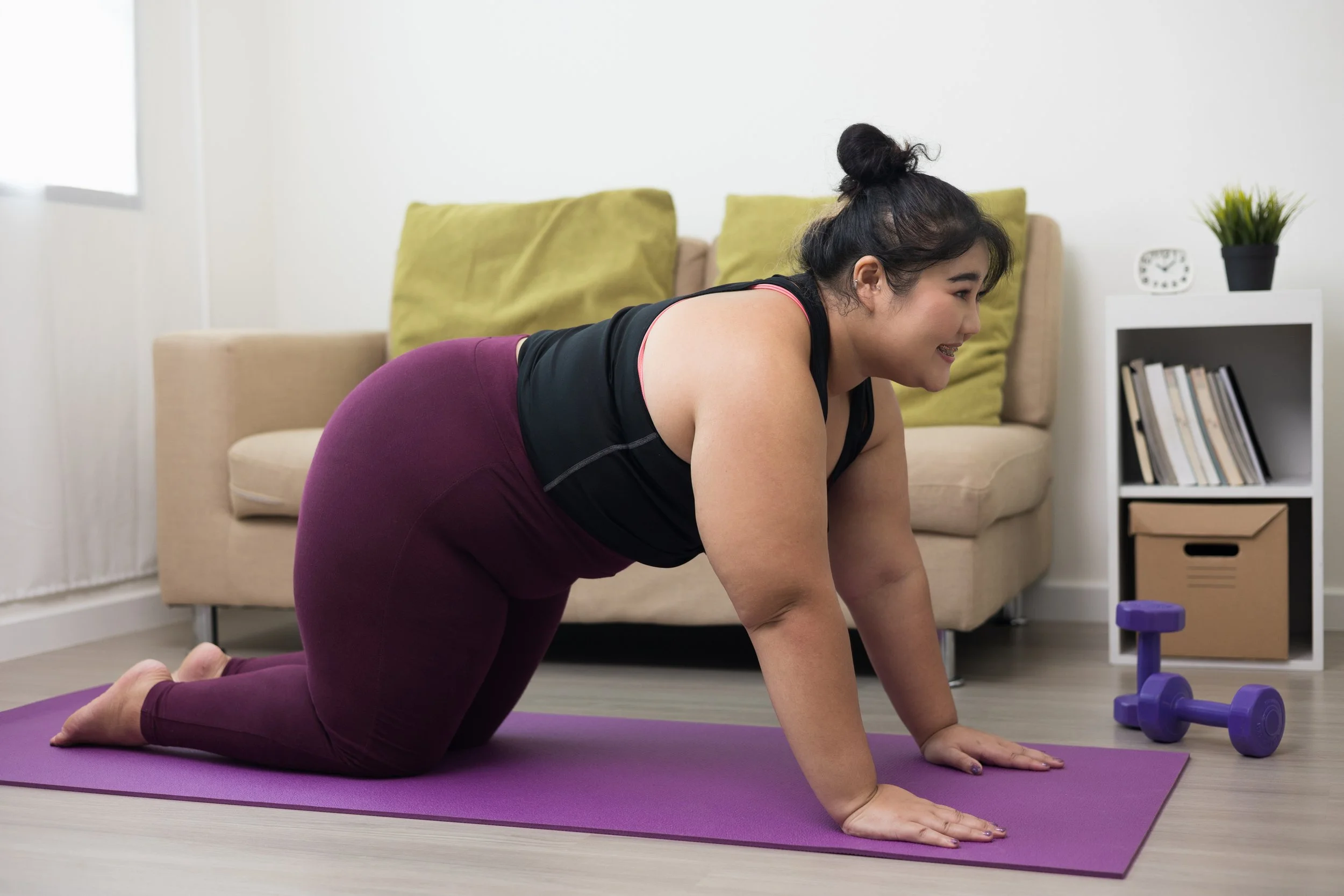 at woman of color doing yoga at home on a fuchsia yoga mat
