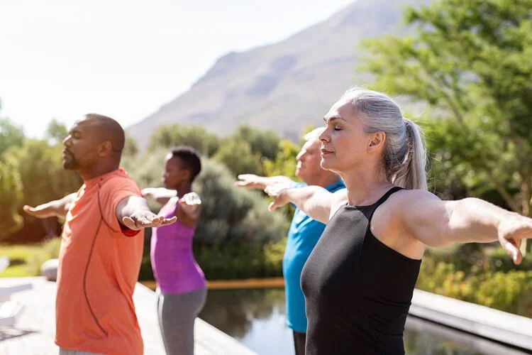 group of people stretching outdoors with a mountain in the background