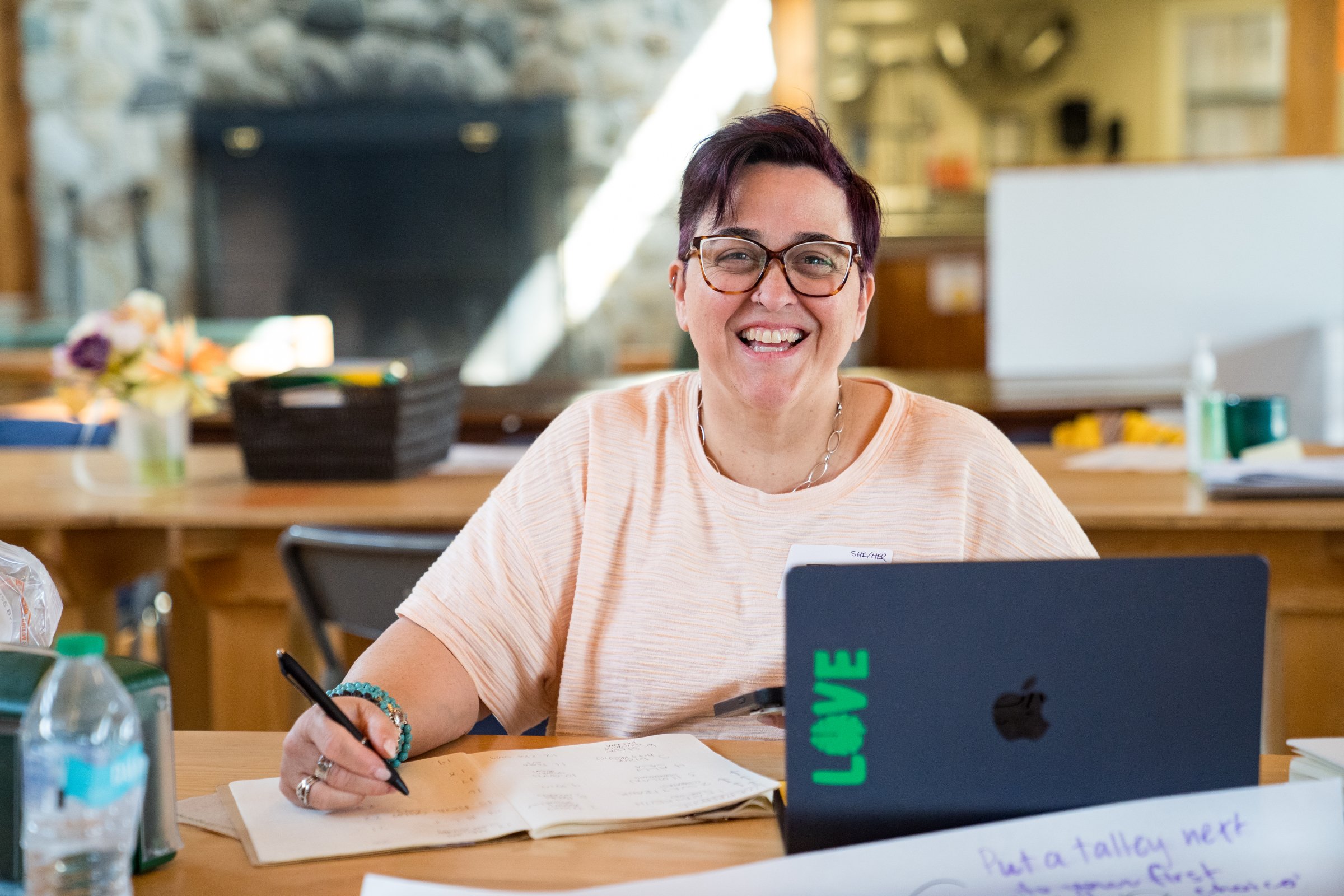 A person seated smiling in front of a computer