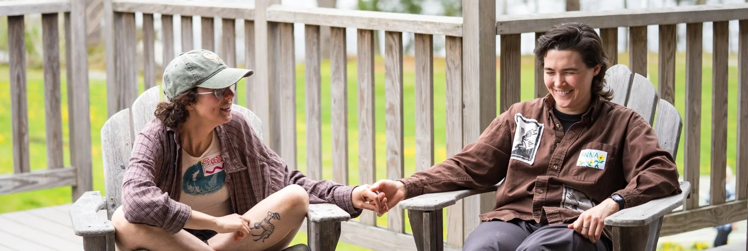 Two white, tattooed individuals sit hand in hand at a brain injury retreat